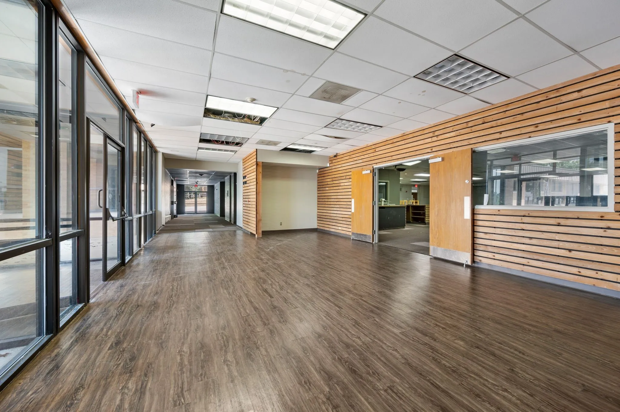 Unfurnished room featuring wood finished floors, wood walls, and a drop ceiling