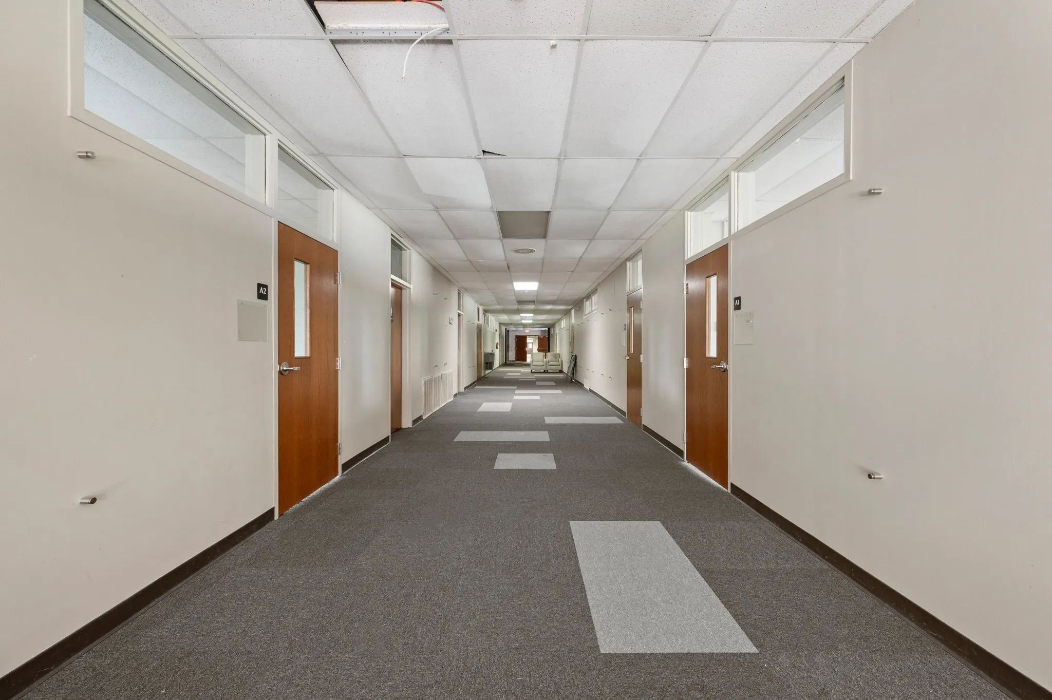 Hallway with a paneled ceiling and carpet