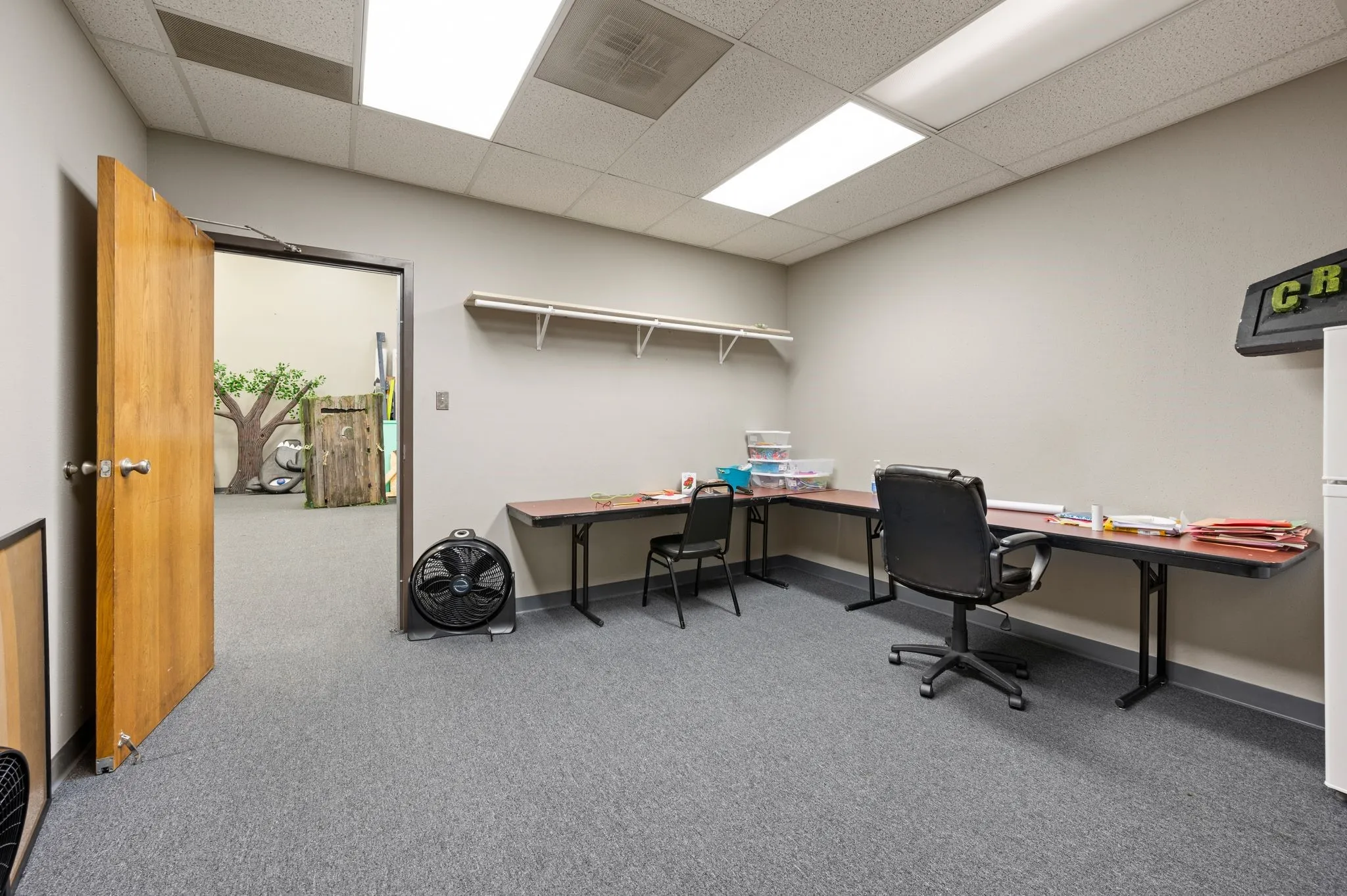 Carpeted office space featuring a drop ceiling and baseboards