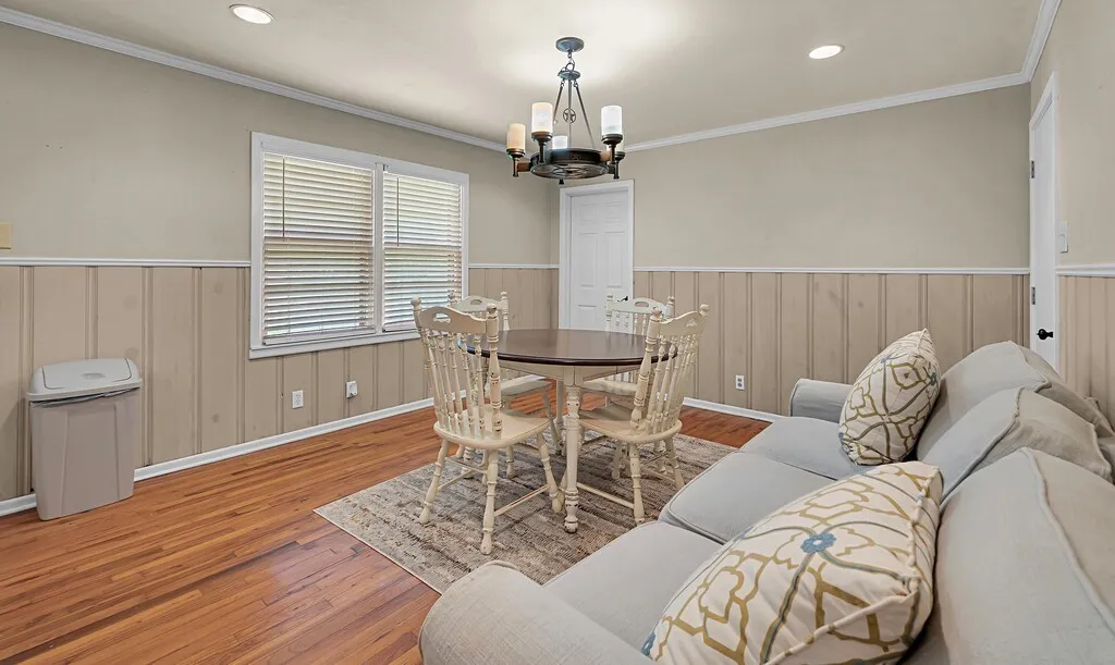 Dining room featuring a chandelier, wood finished floors, a wainscoted wall, ornamental molding, and recessed lighting