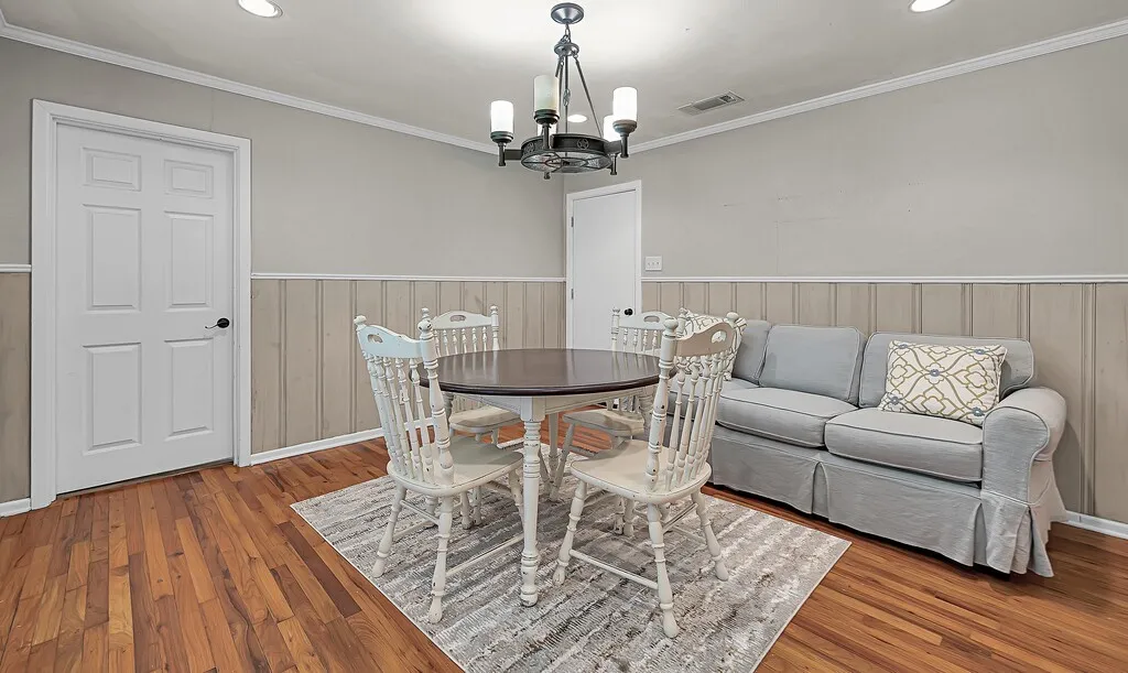 Dining space featuring a chandelier, wood finished floors, a wainscoted wall, ornamental molding, and recessed lighting
