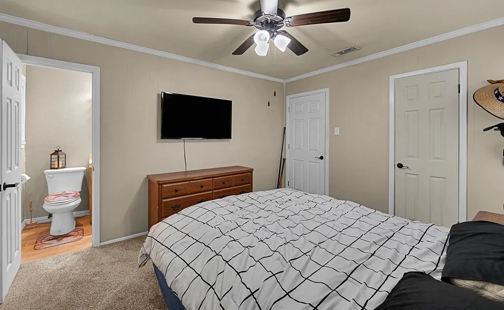 Bedroom featuring ornamental molding, light colored carpet, ceiling fan, and ensuite bathroom