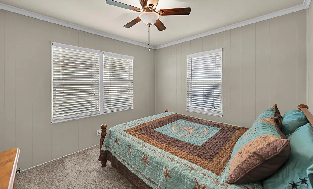 Carpeted bedroom with ornamental molding and a ceiling fan