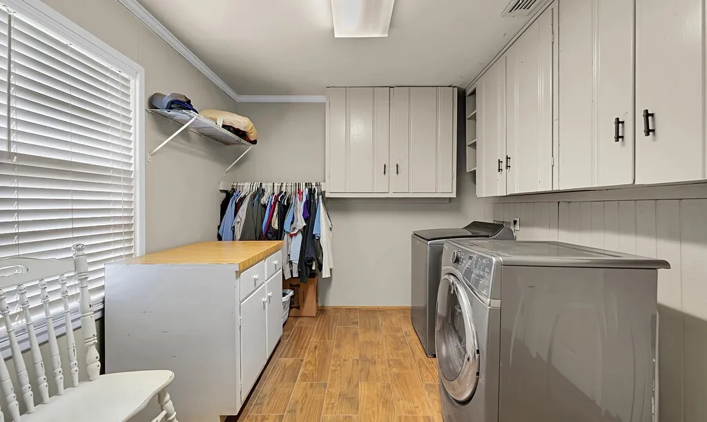 Laundry area featuring washer and clothes dryer, cabinet space, light wood finished floors, and ornamental molding