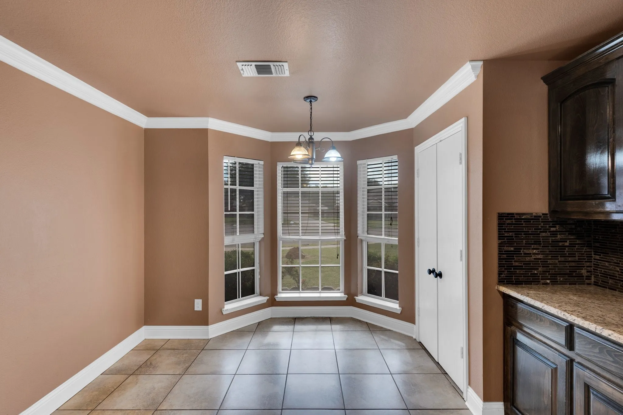 Unfurnished dining area with light tile patterned flooring and crown molding