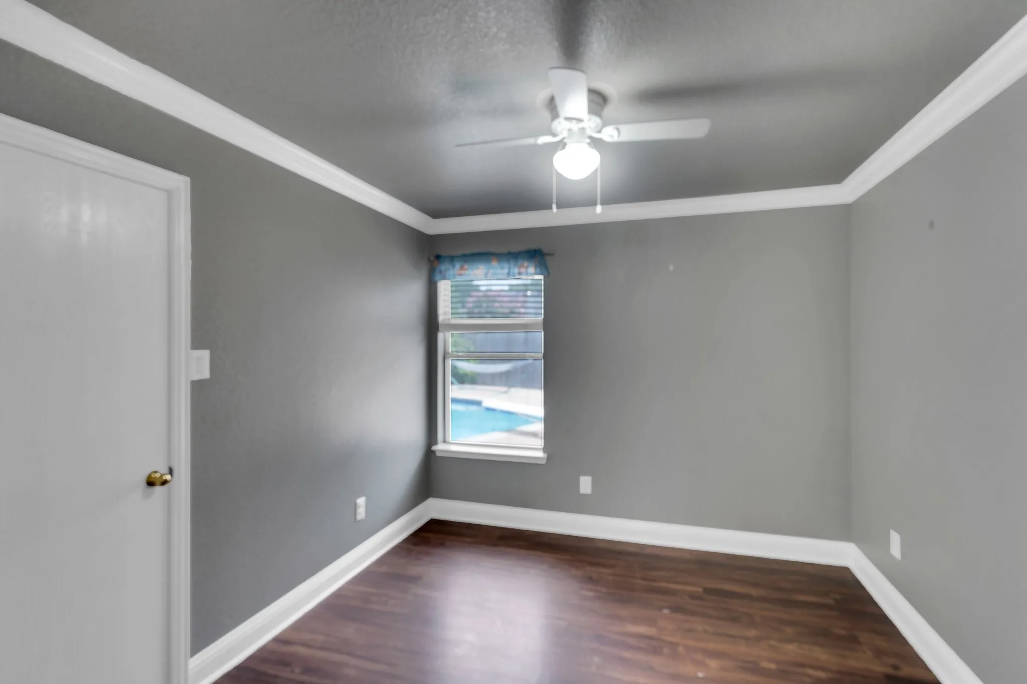 Unfurnished room featuring ceiling fan, ornamental molding, and wood finished floors