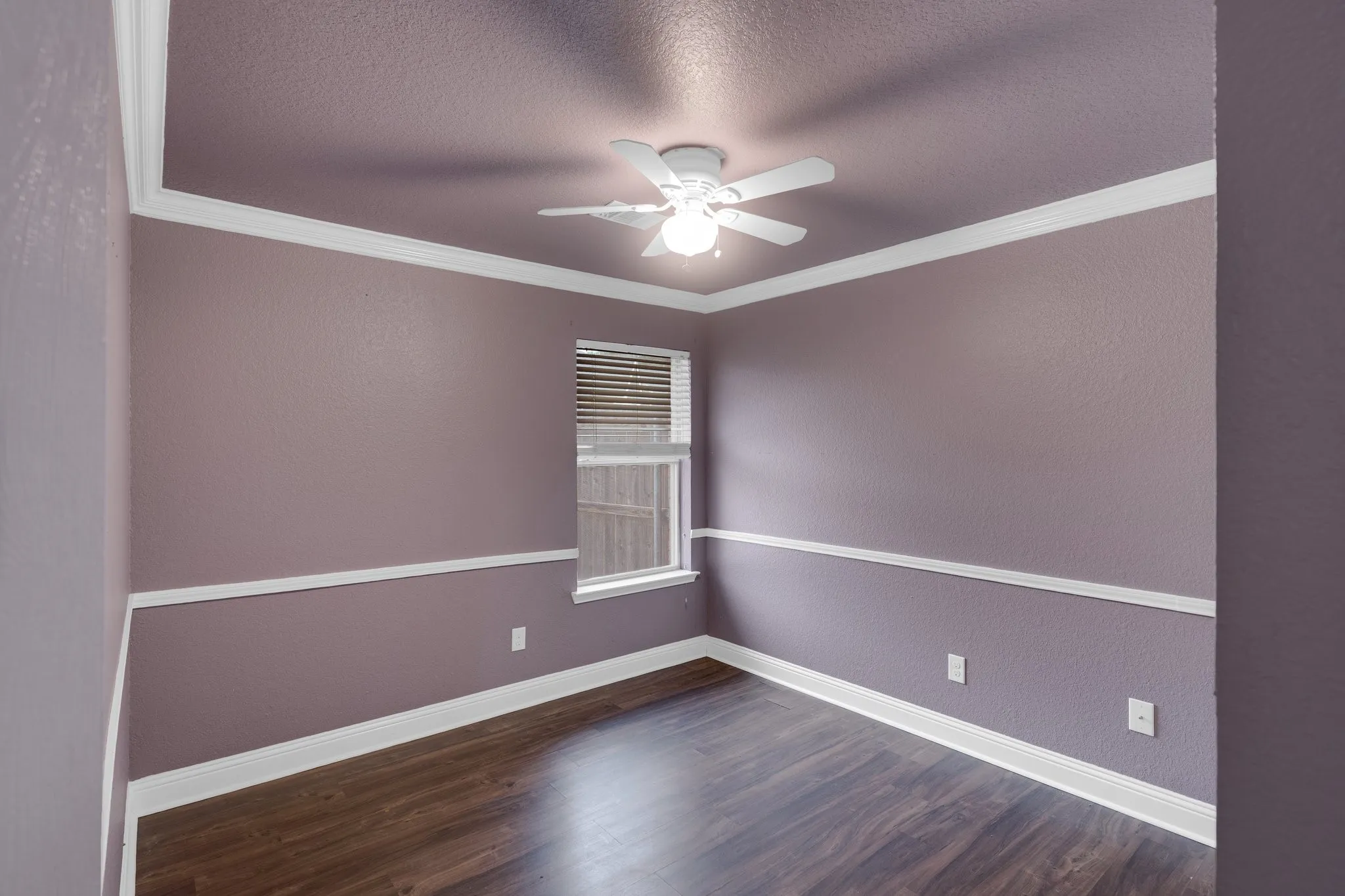 Empty room with dark wood finished floors, crown molding, ceiling fan, and a textured ceiling