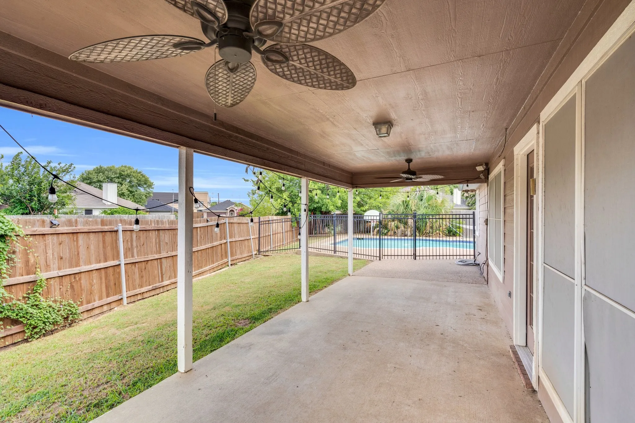 Fenced backyard featuring a ceiling fan and a patio area