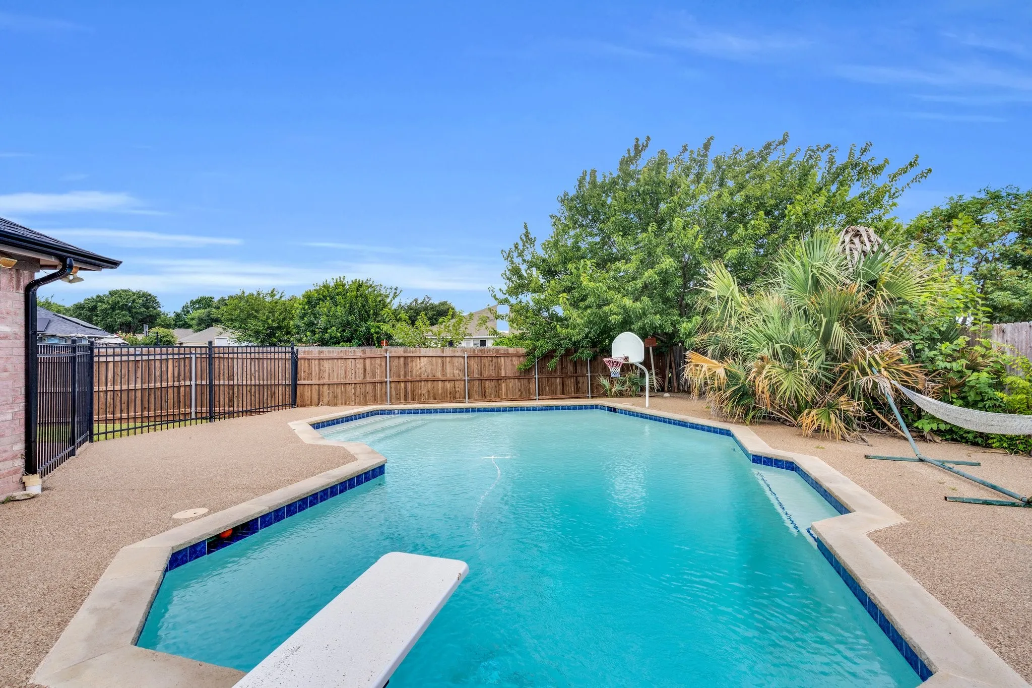 View of pool with a fenced backyard, a diving board, and a patio