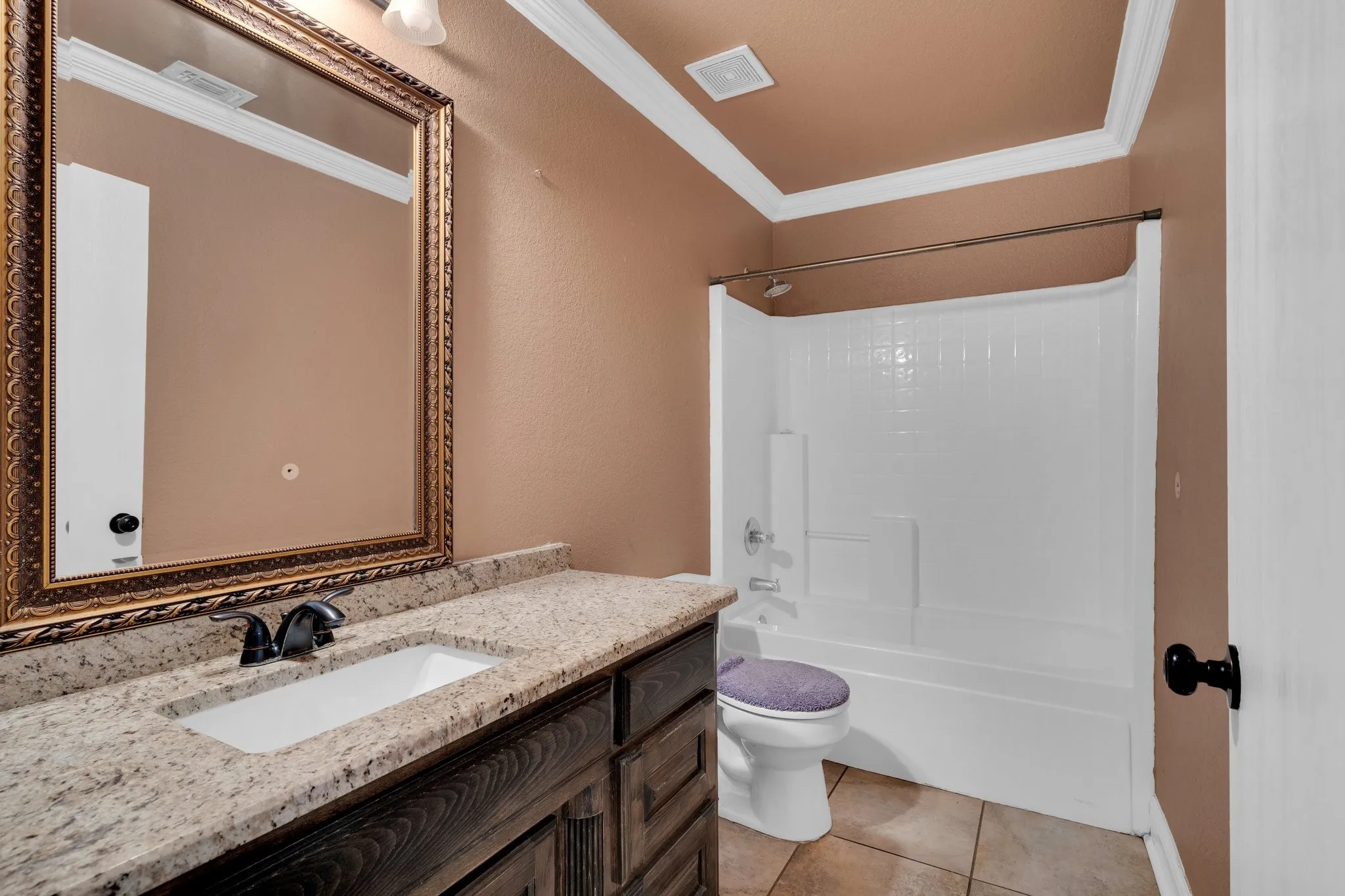 Full bath with vanity, ornamental molding, tile patterned floors, and shower / tub combination