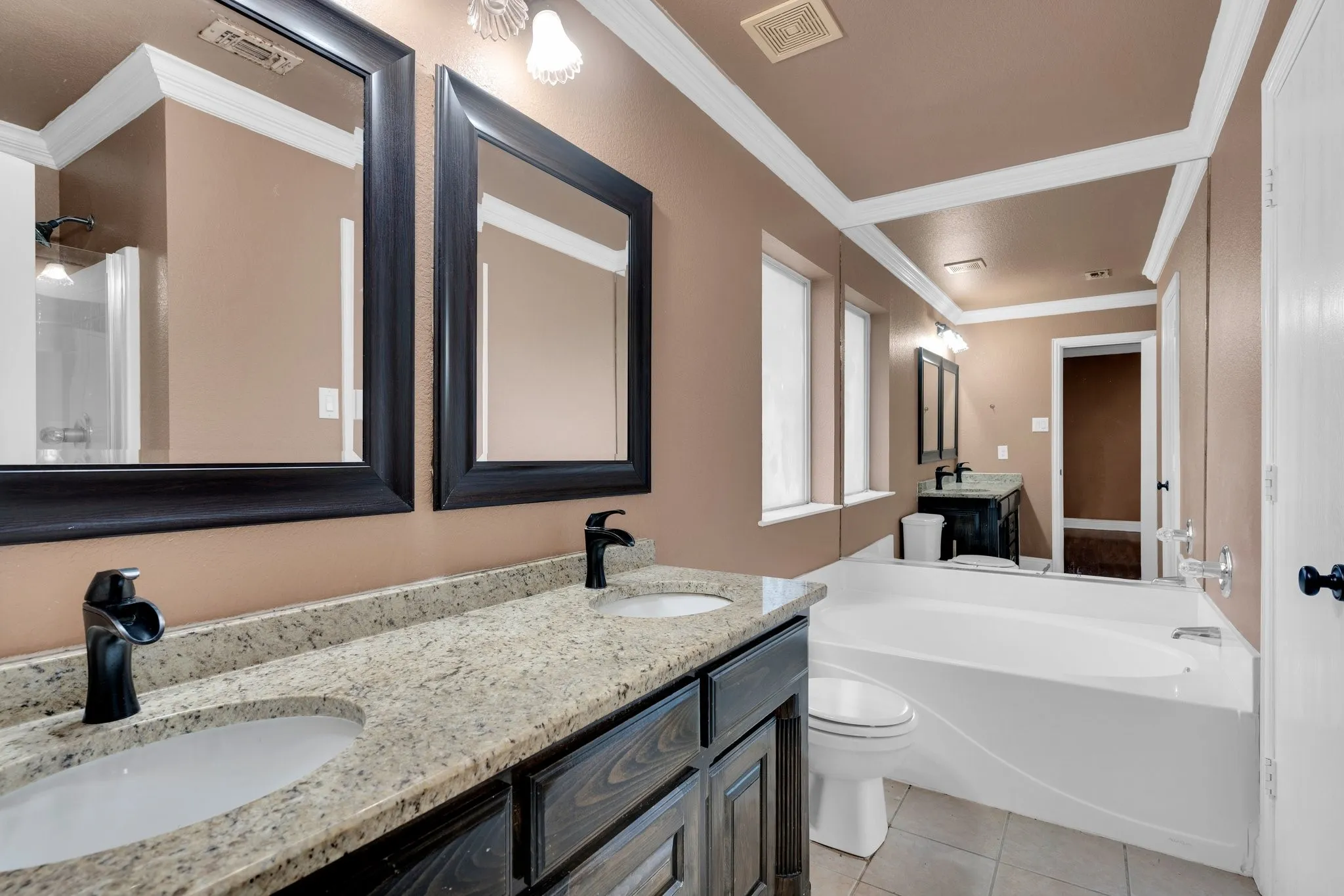 Full bath with double vanity, tile patterned flooring, a bath, and ornamental molding