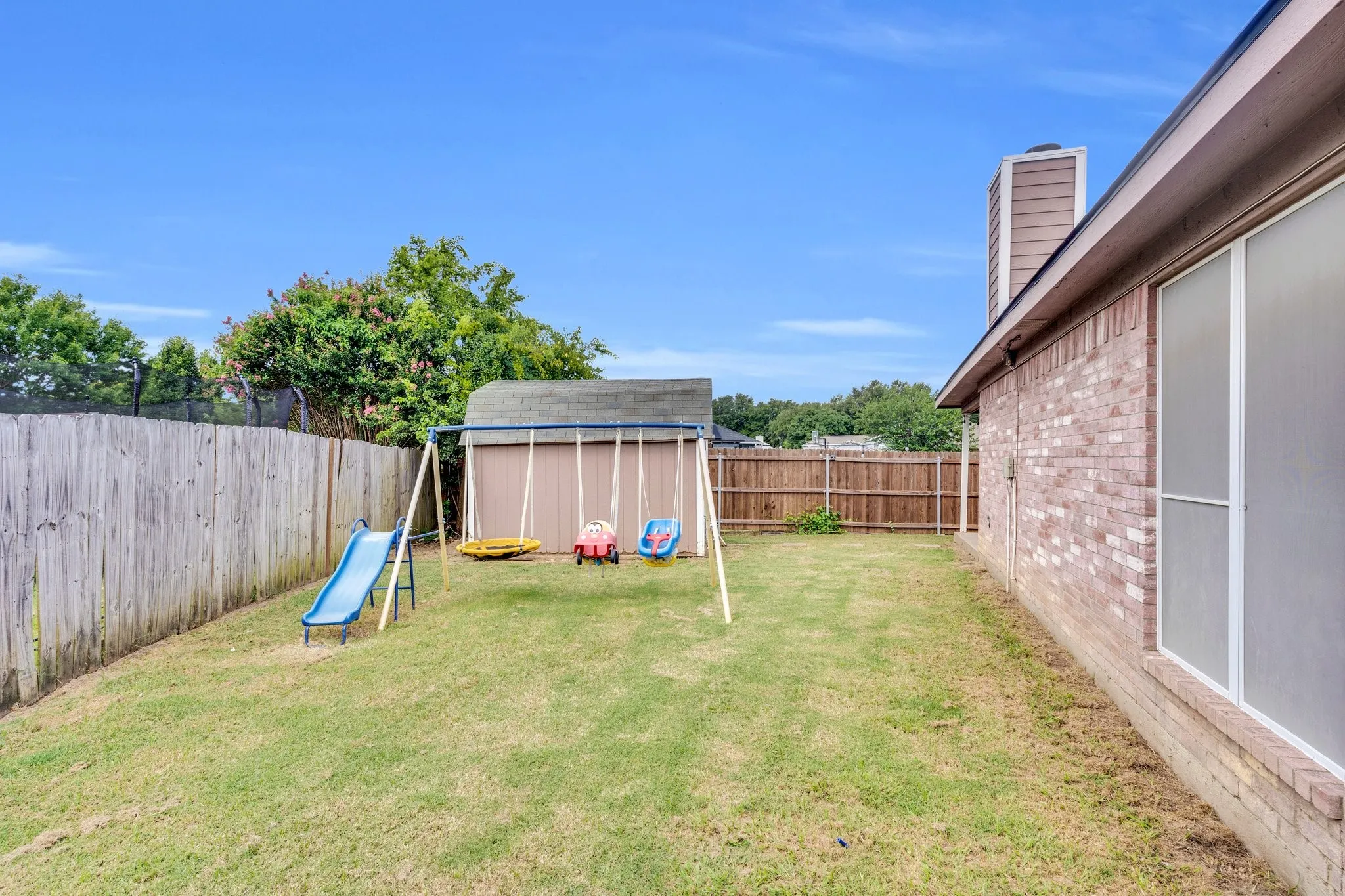 Fenced backyard featuring a storage shed