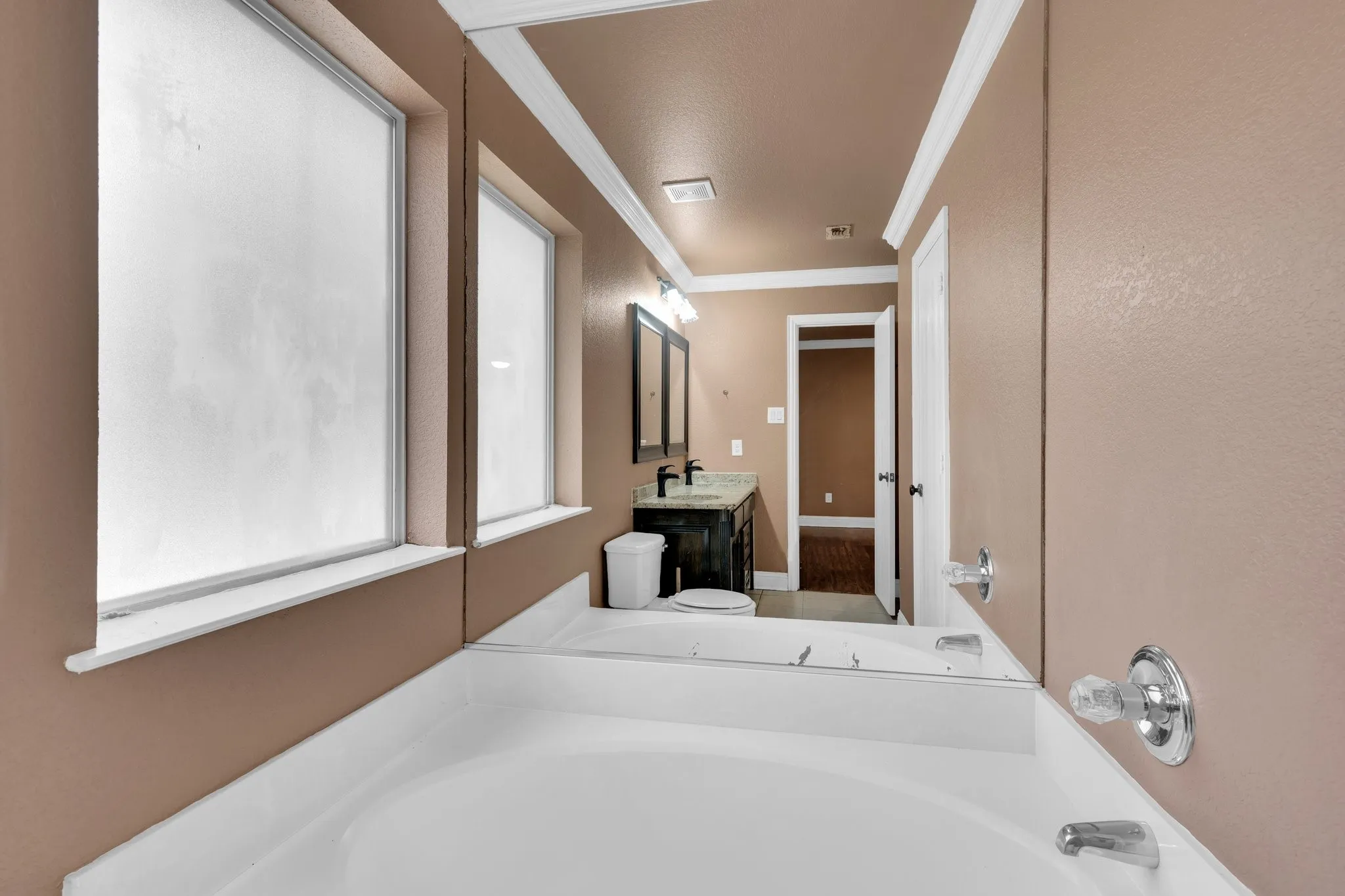 Bathroom with a bath, ornamental molding, and vanity