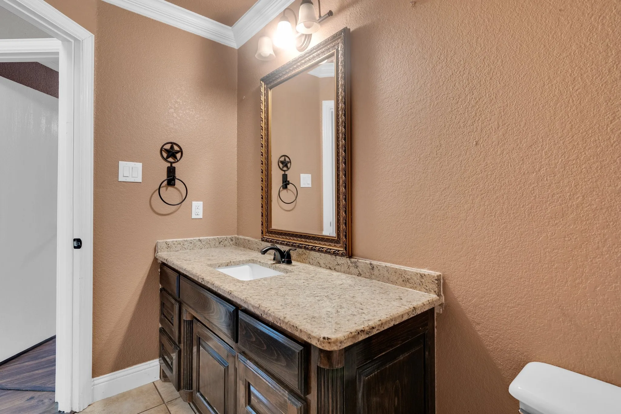 Bathroom with ornamental molding, vanity, a textured wall, and tile patterned floors