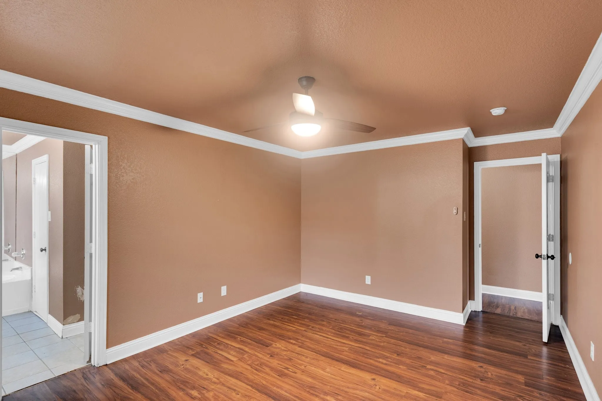 Unfurnished room featuring a ceiling fan, crown molding, dark wood-type flooring, a textured ceiling, and a smoke detector
