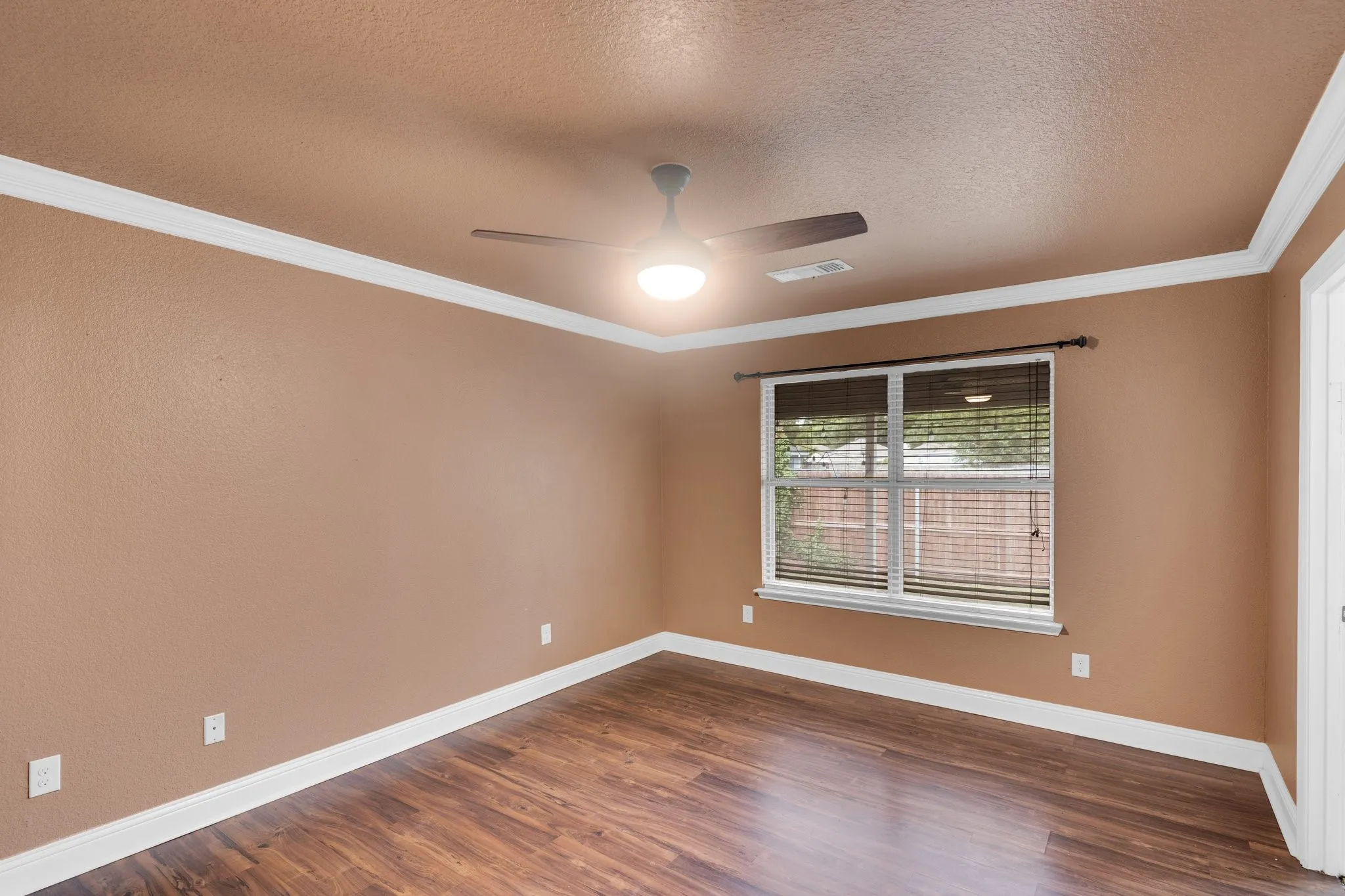 Empty room with a textured ceiling, ceiling fan, dark wood-type flooring, and ornamental molding