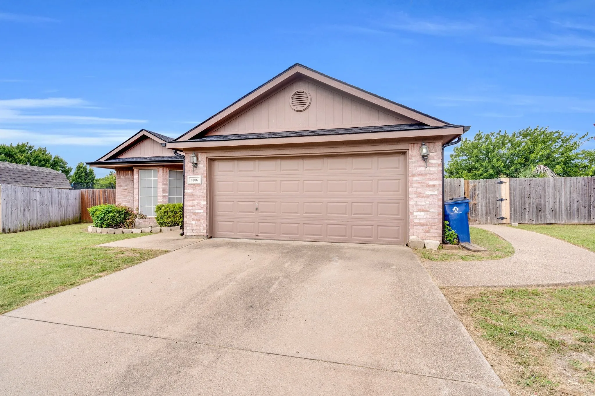 Single story home with brick siding, driveway, and an attached garage