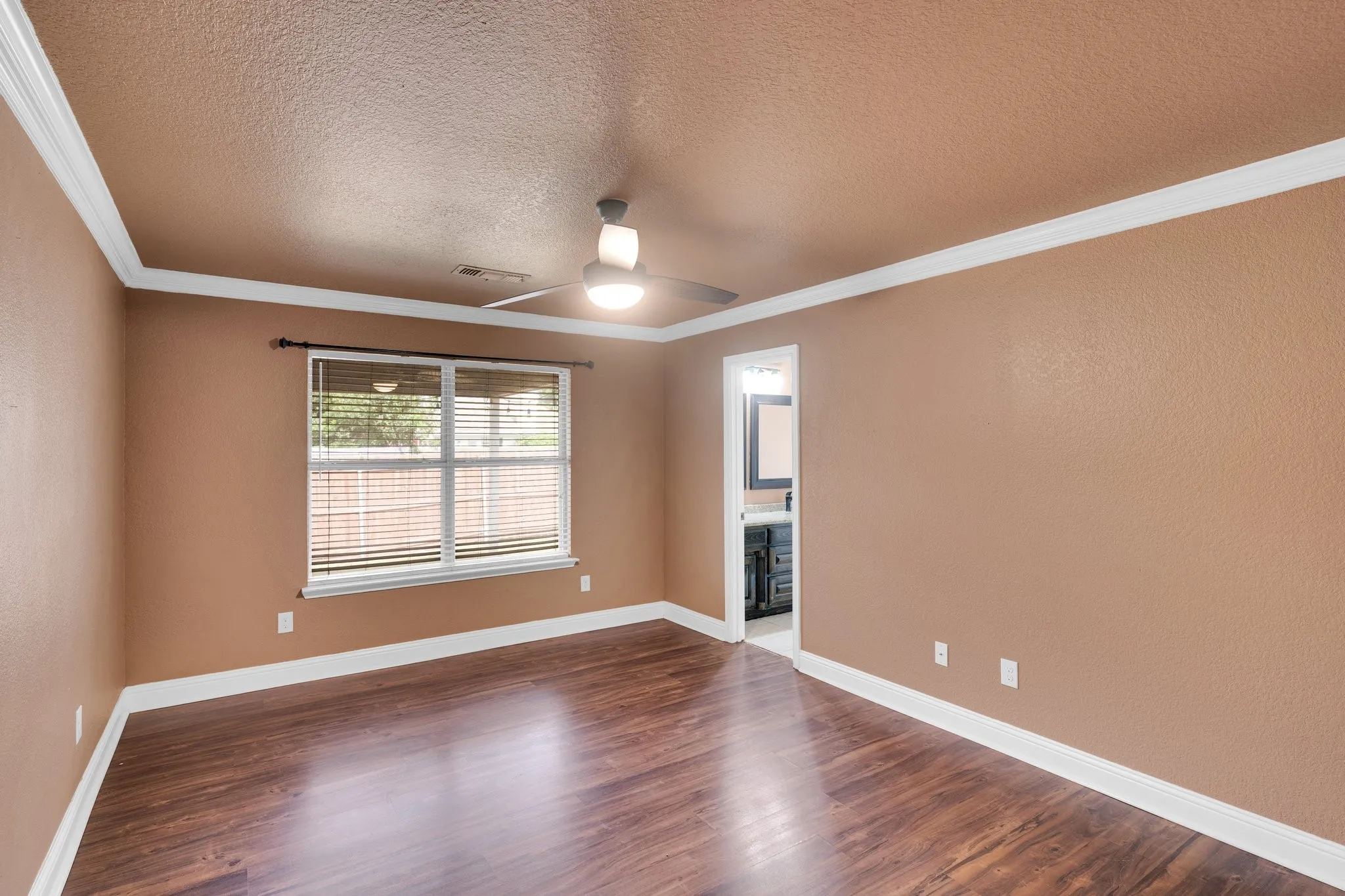 Spare room featuring a ceiling fan, dark wood-type flooring, ornamental molding, and a textured ceiling