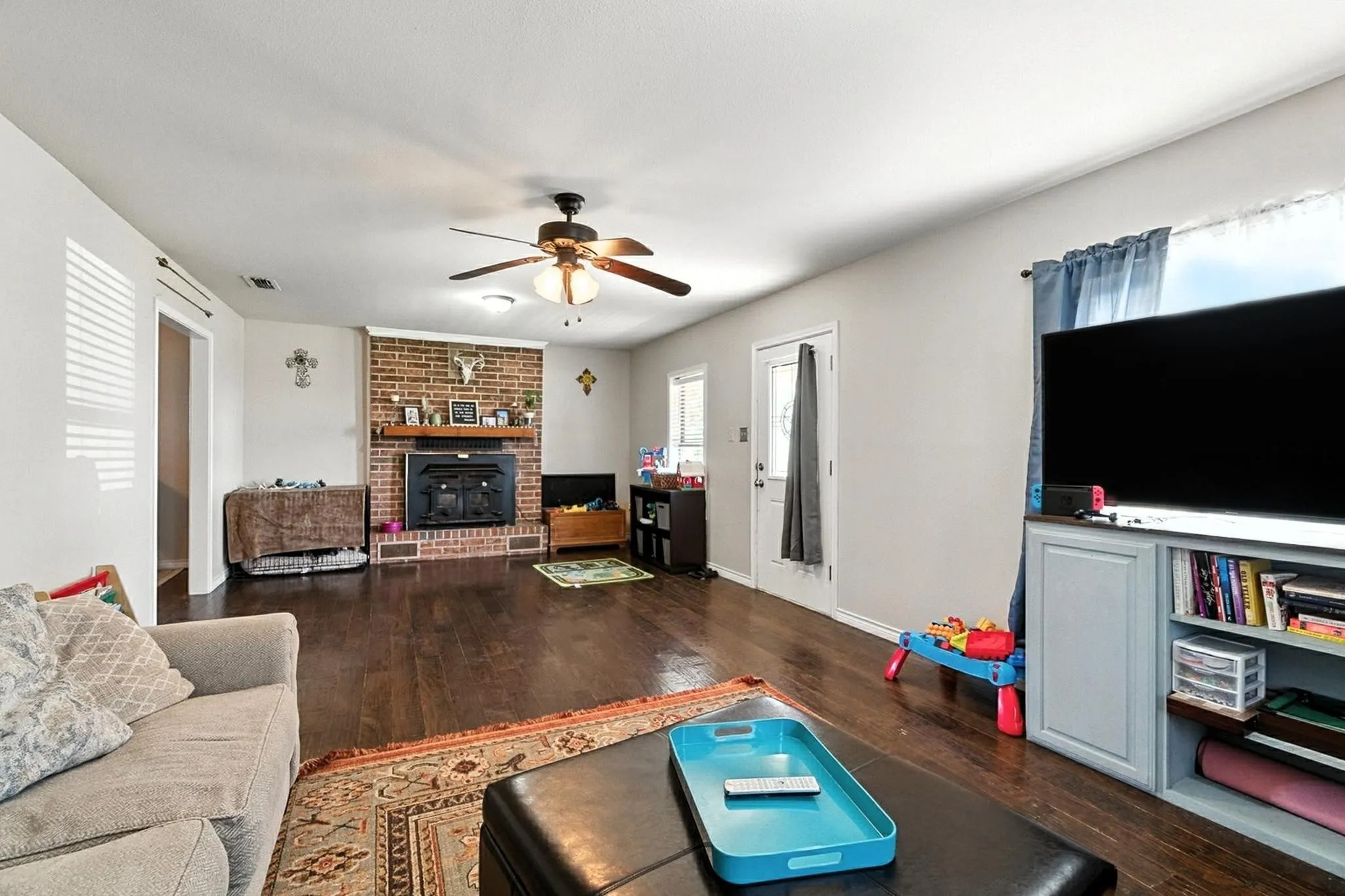 Living area featuring ceiling fan, hardwood / wood-style floors, and a brick fireplace