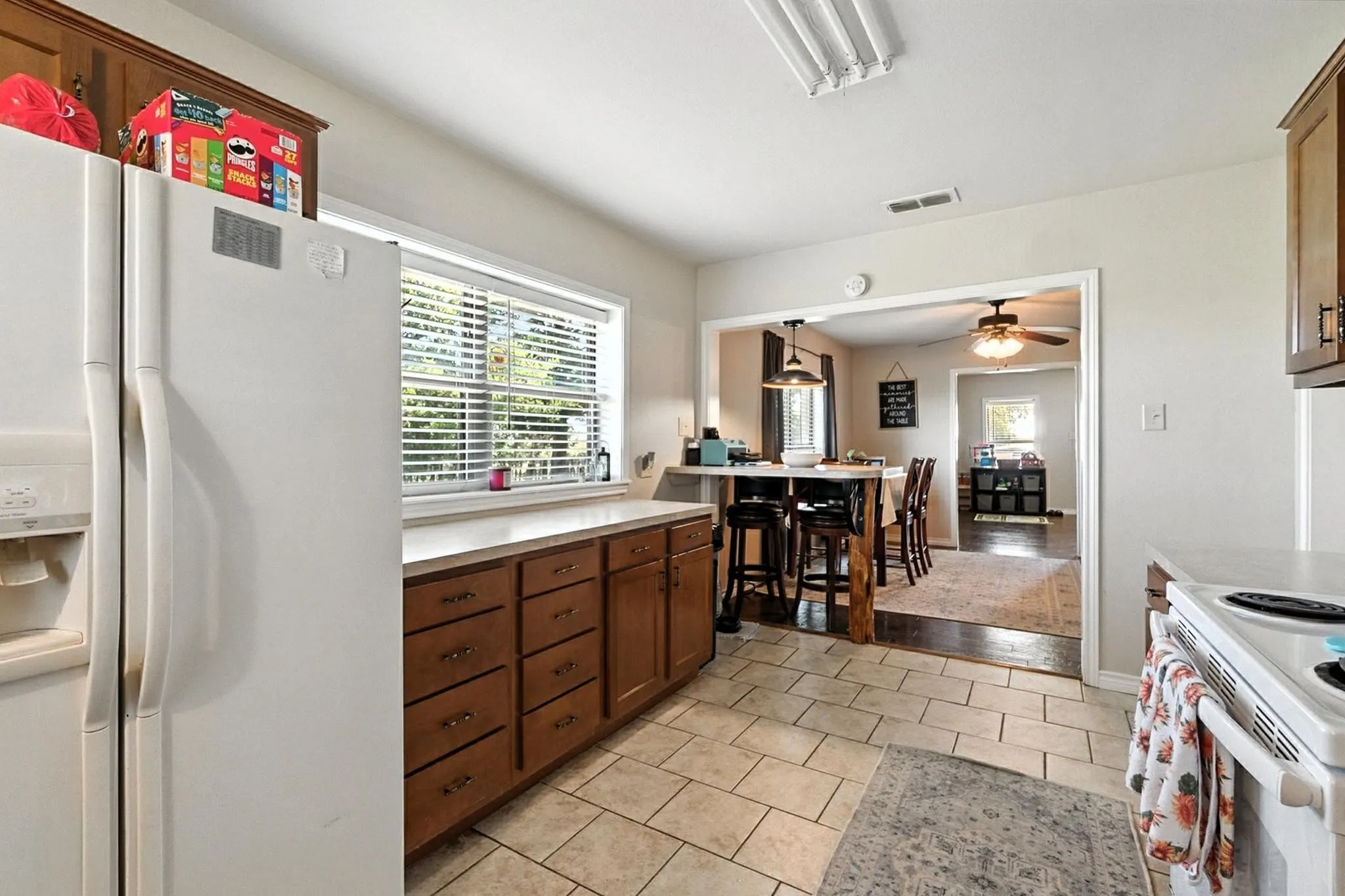 Kitchen featuring white appliances, light countertops, light tile patterned flooring, and ceiling fan