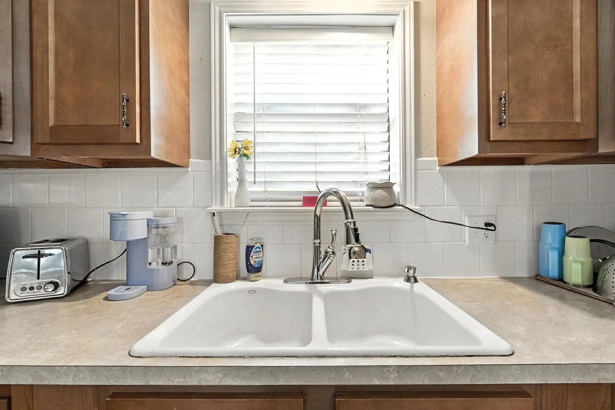 Kitchen view of brown cabinets, light countertops, and tasteful backsplash