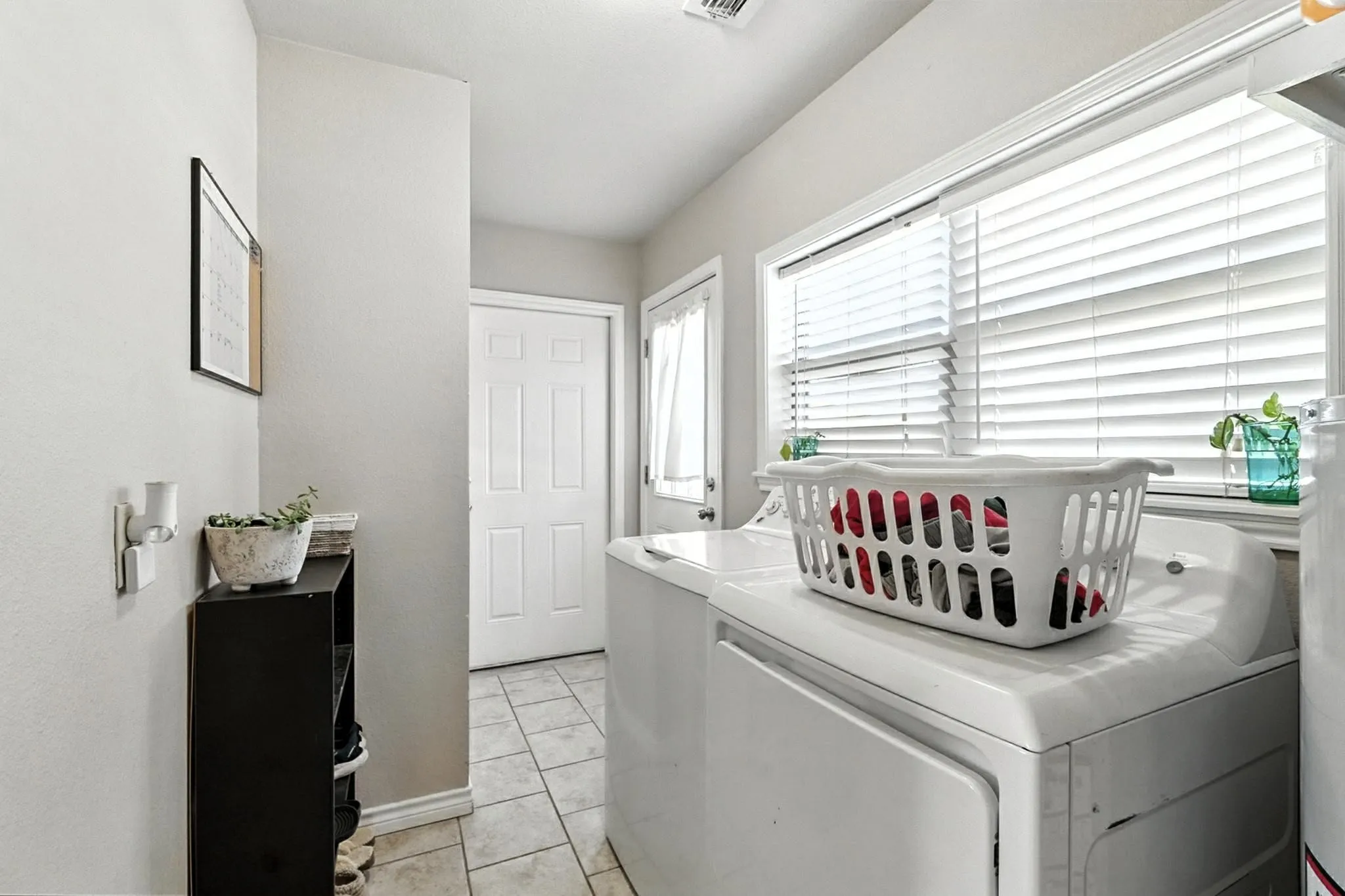 Washroom with washing machine and clothes dryer and light tile patterned floors
