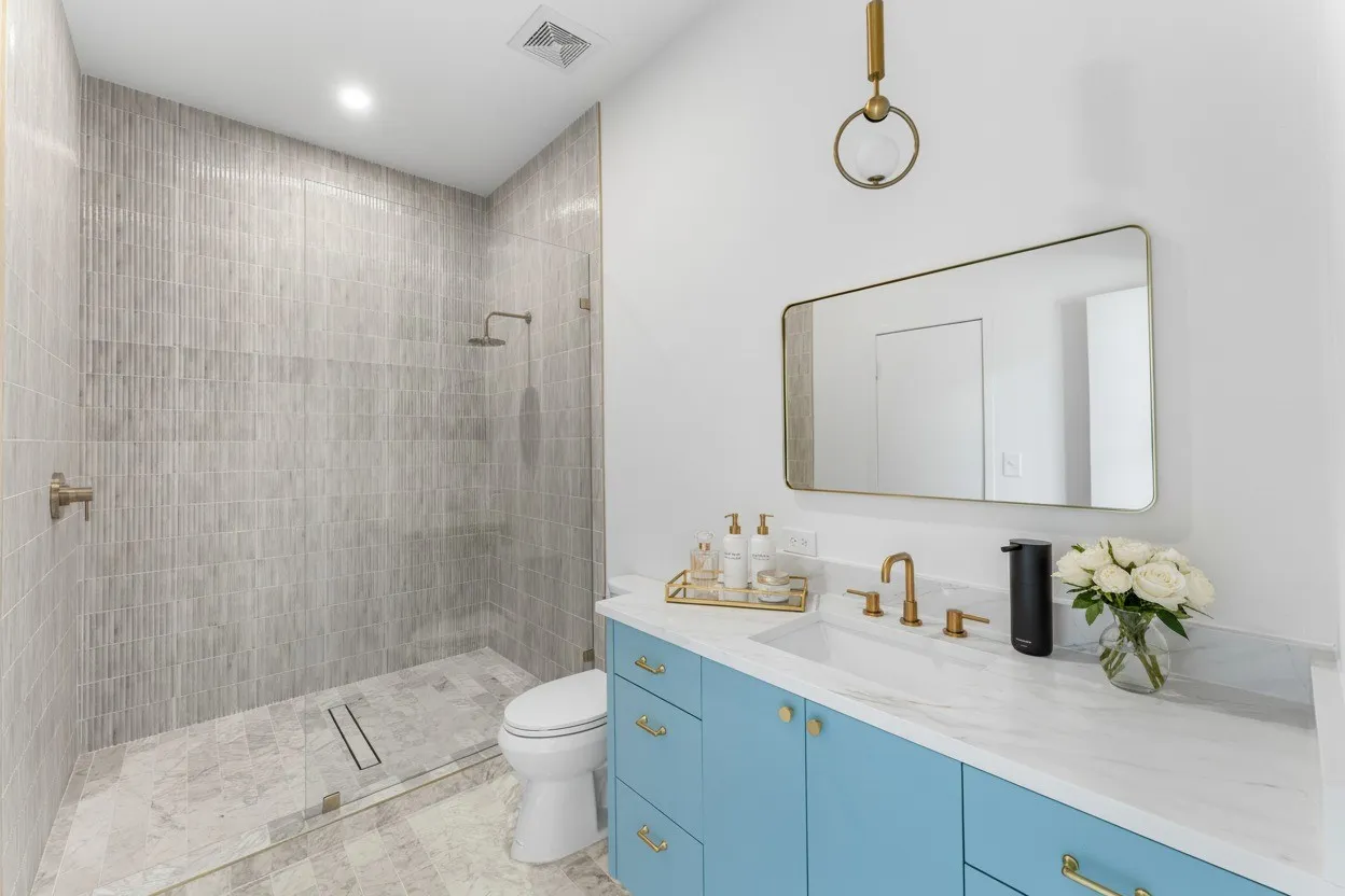 Bathroom with tiled shower, vanity, and recessed lighting