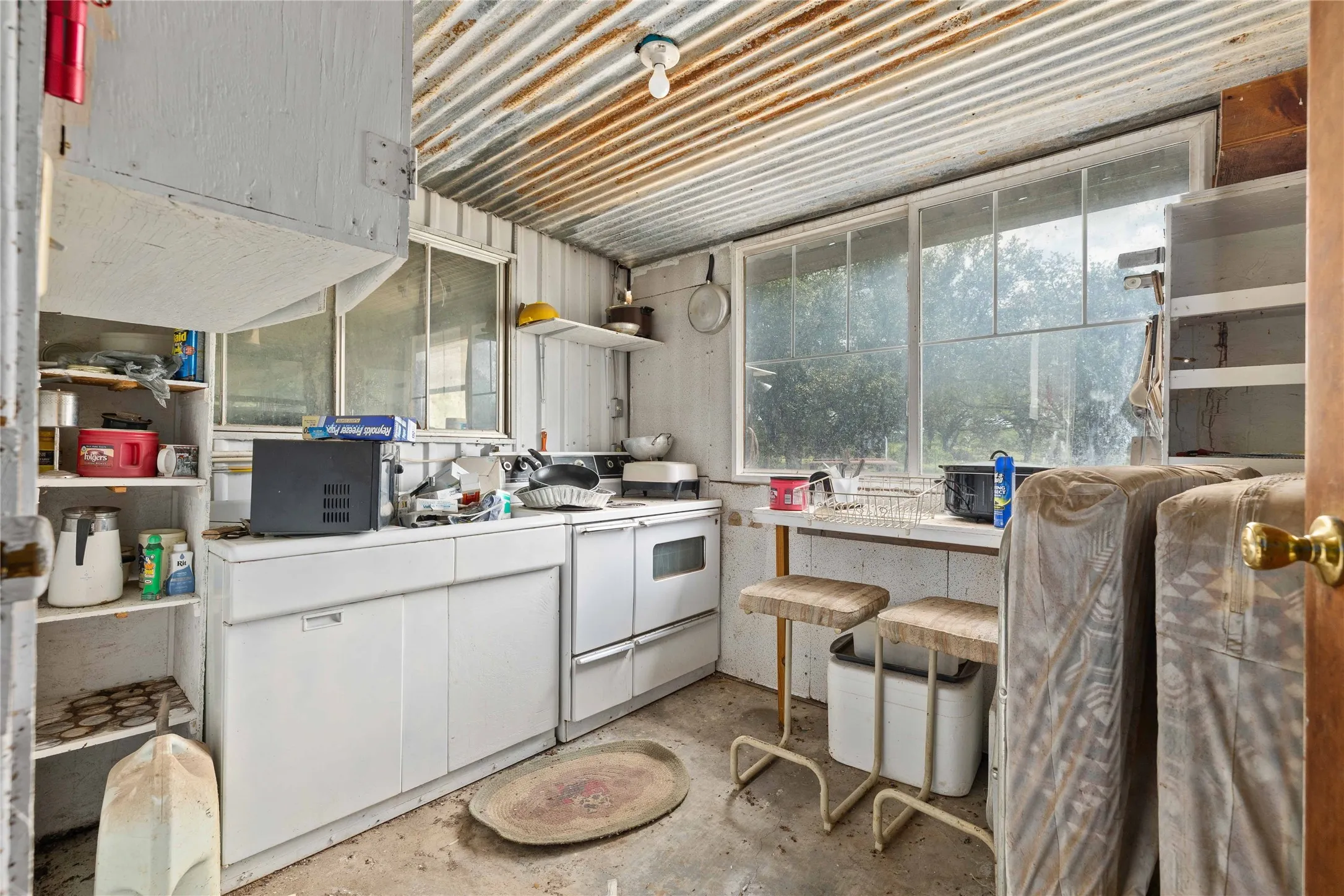 Kitchen with white electric range oven, unfinished concrete flooring, and white cabinetry
