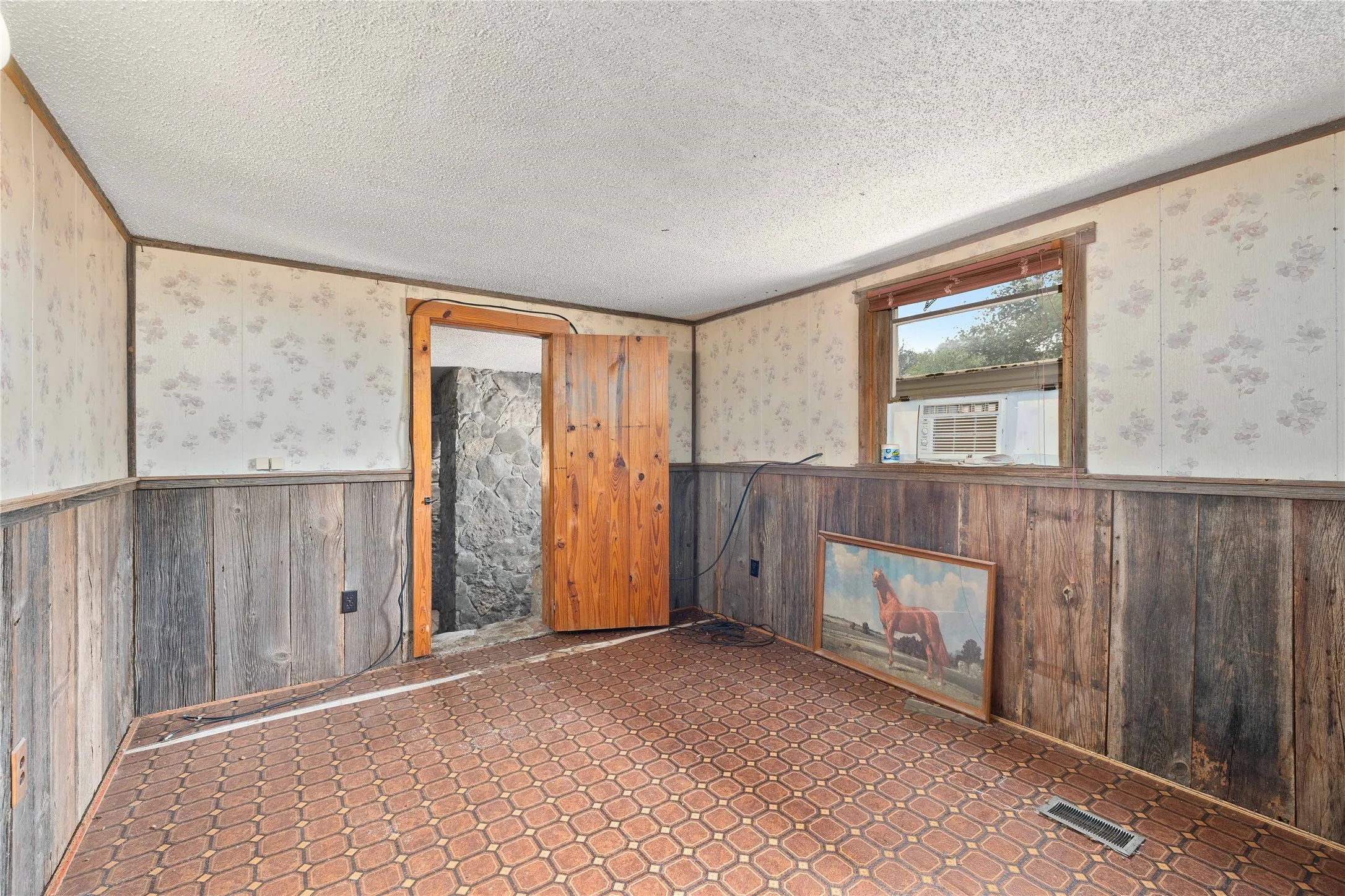 Unfurnished room with wainscoting, a textured ceiling, and cooling unit