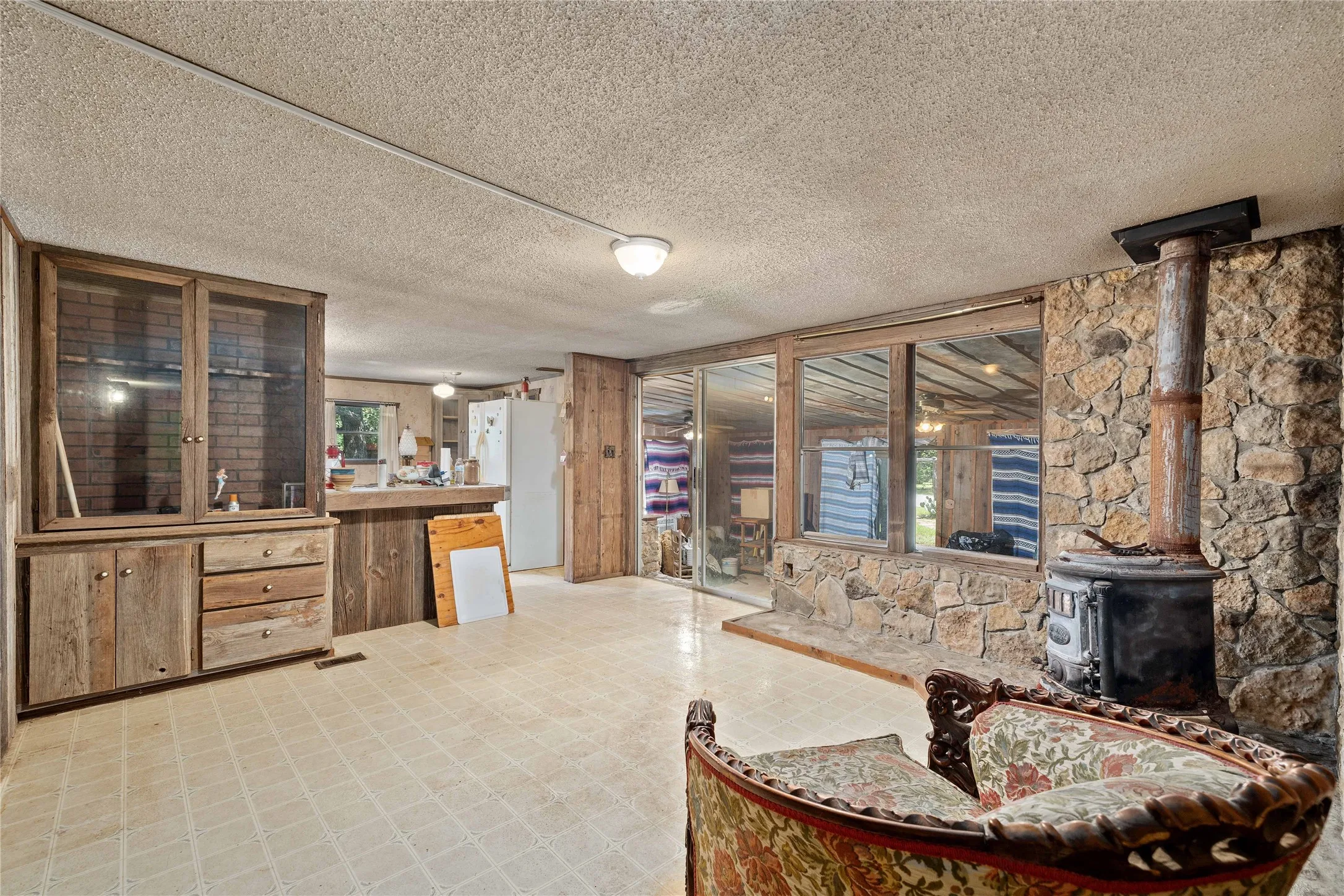 Living area featuring a wood stove, a textured ceiling, and light floors