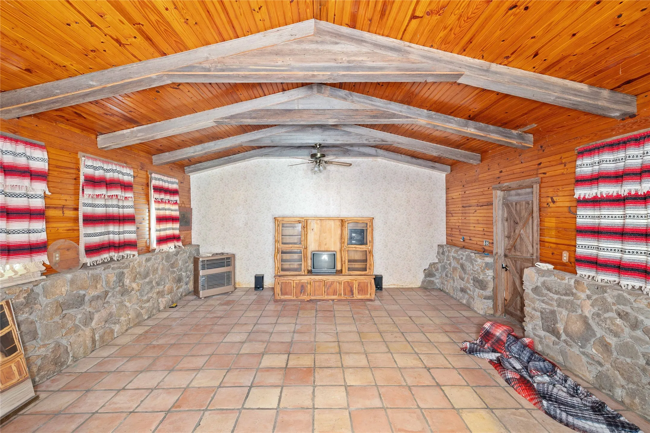 Unfurnished living room with a ceiling fan, heating unit, and wooden walls