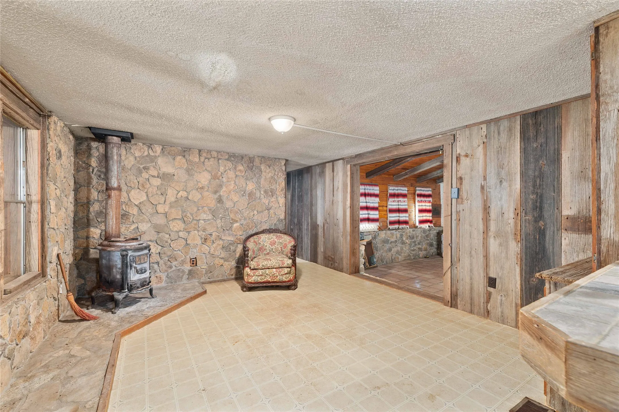 Sitting room with wood walls, a textured ceiling, and a wood stove