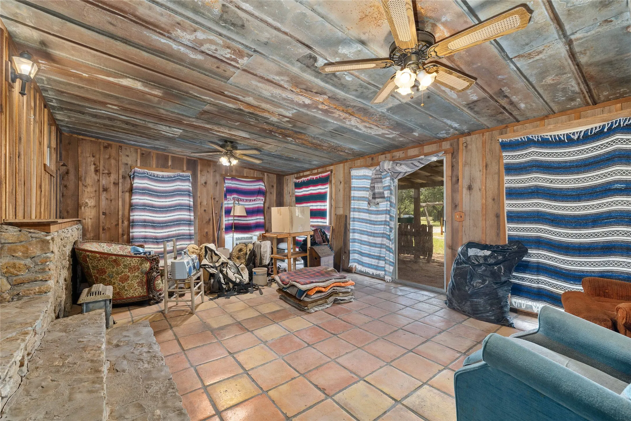 Living area with a ceiling fan, wooden ceiling, wood walls, and tile patterned floors