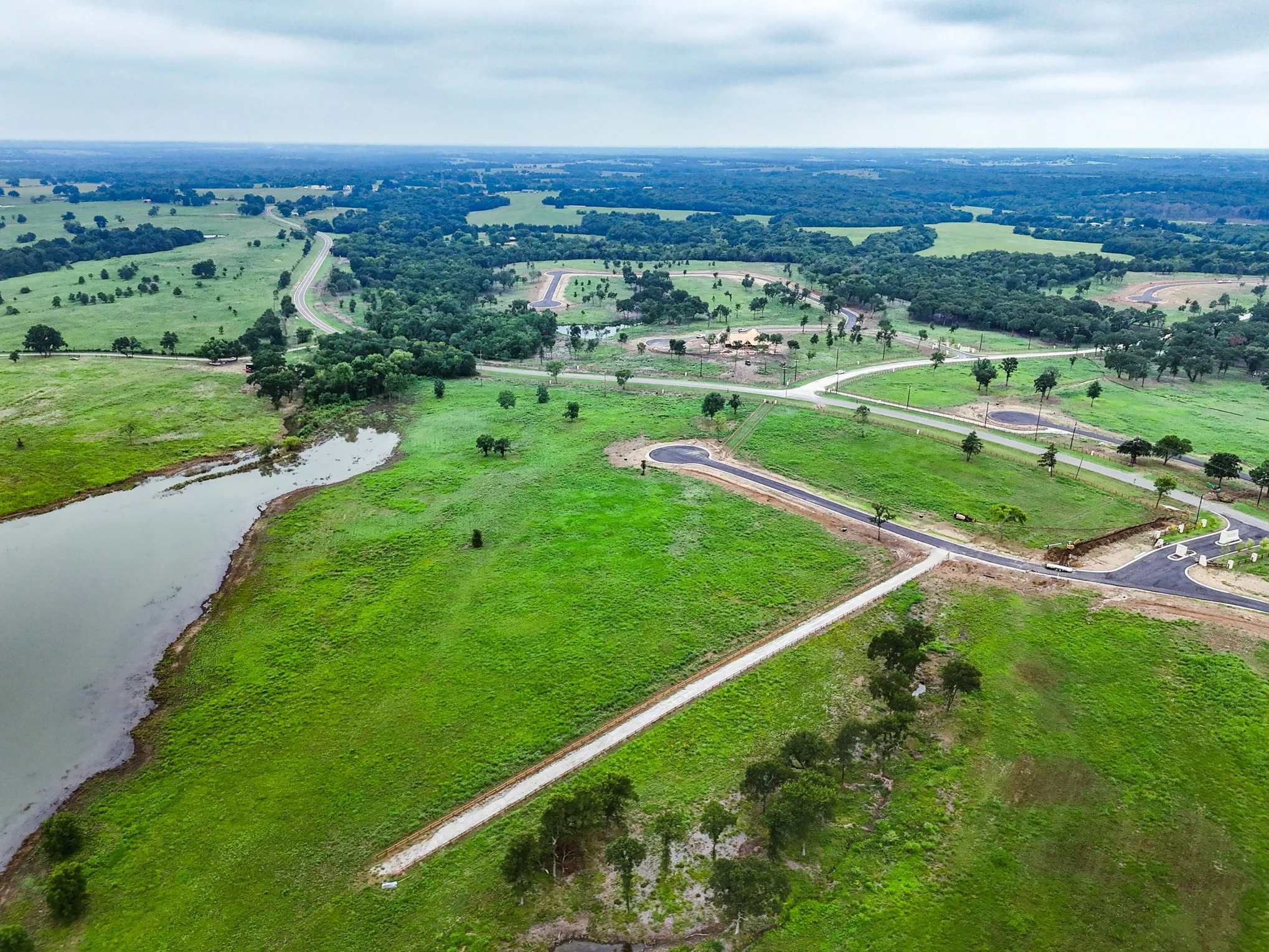 Aerial view of property and surrounding area featuring rural landscape and a nearby body of water