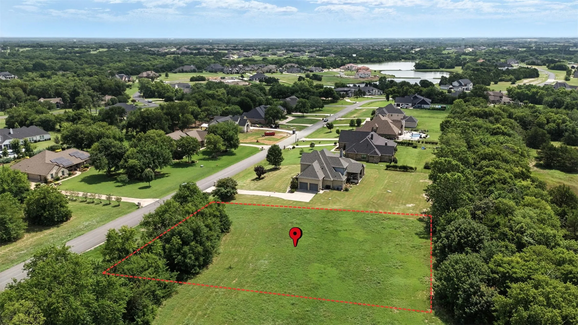 Aerial perspective of suburban area with property parcel outlined and a large body of water