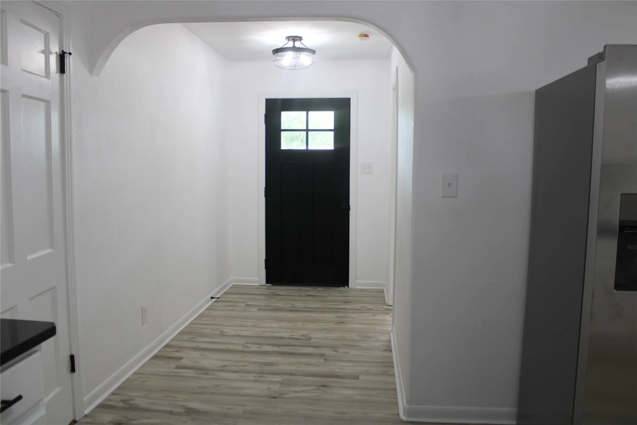 Doorway featuring arched walkways and light wood-type flooring
