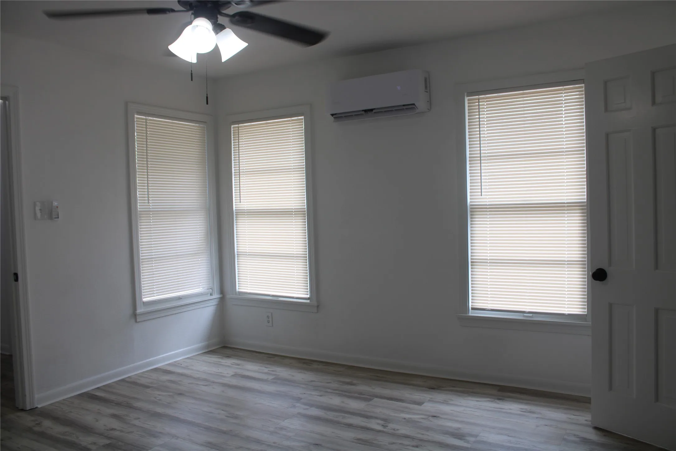 Empty room with a wall mounted air conditioner, ceiling fan, and wood finished floors