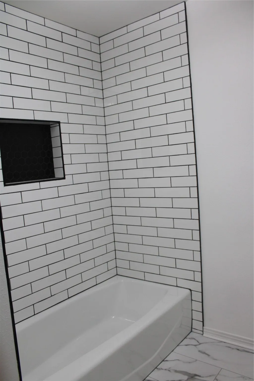 Full bath with marble finish floors and shower / tub combination