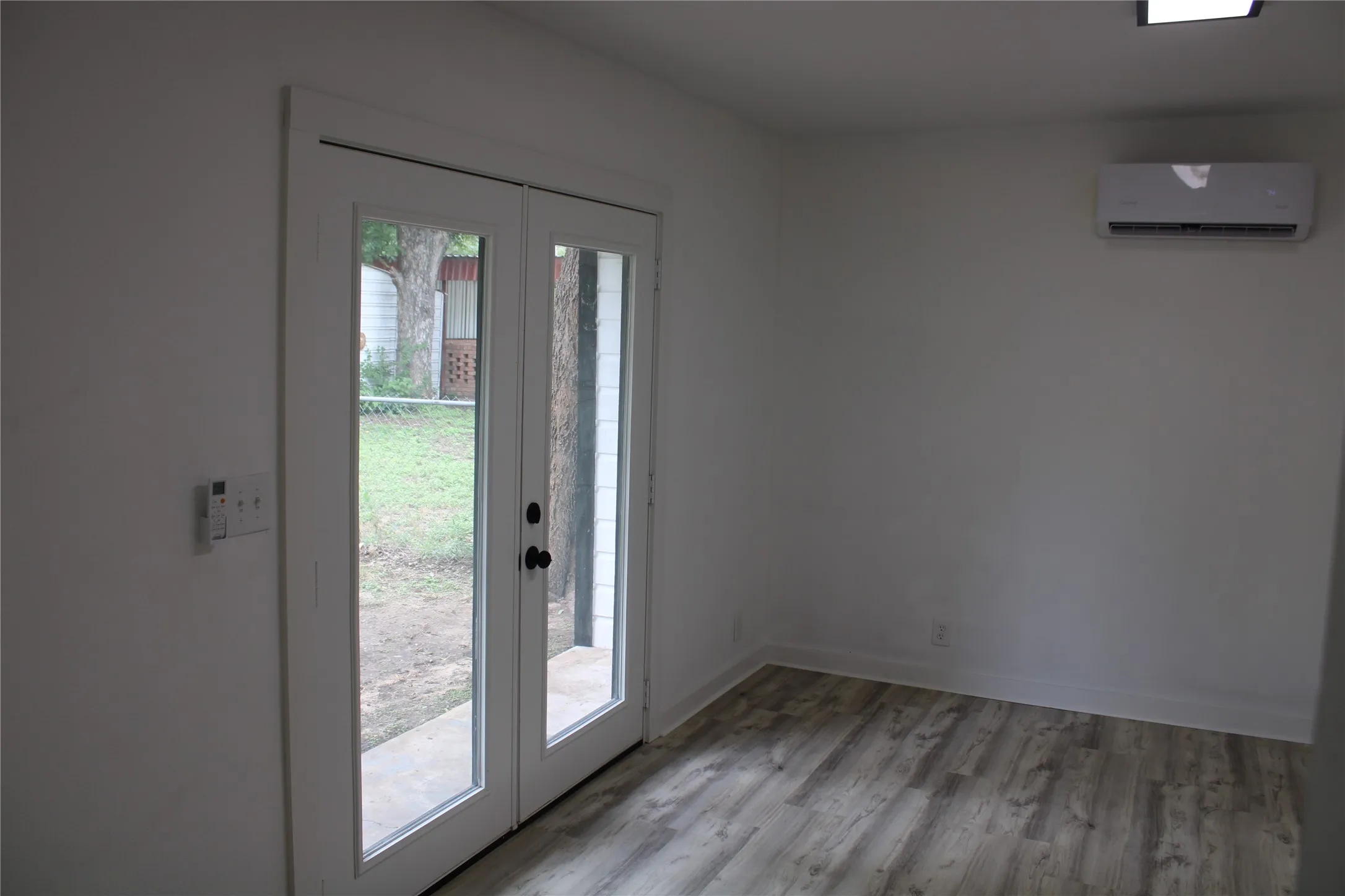 Doorway to outside with an AC wall unit and light wood-type flooring