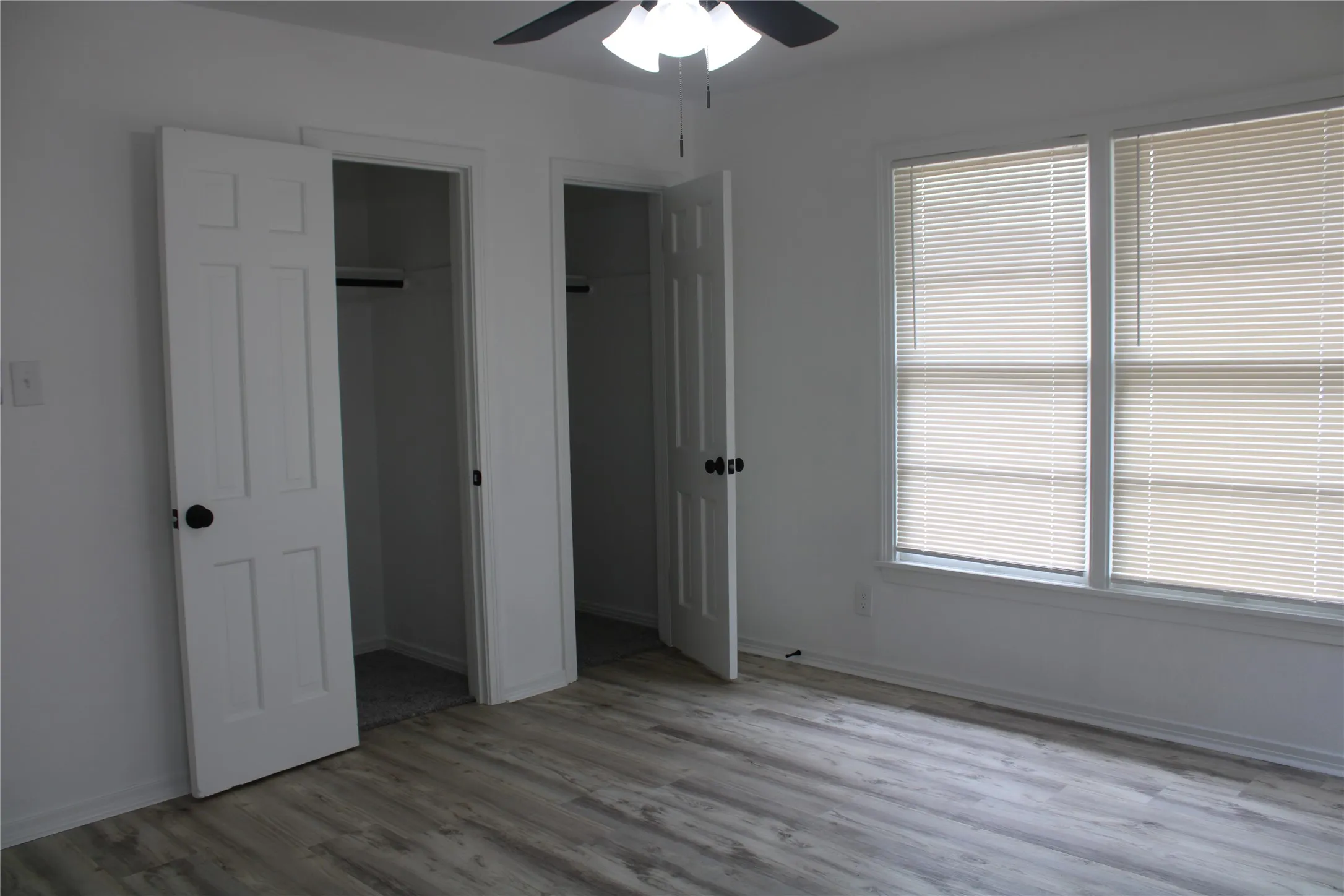 Unfurnished bedroom featuring wood finished floors, multiple closets, and ceiling fan