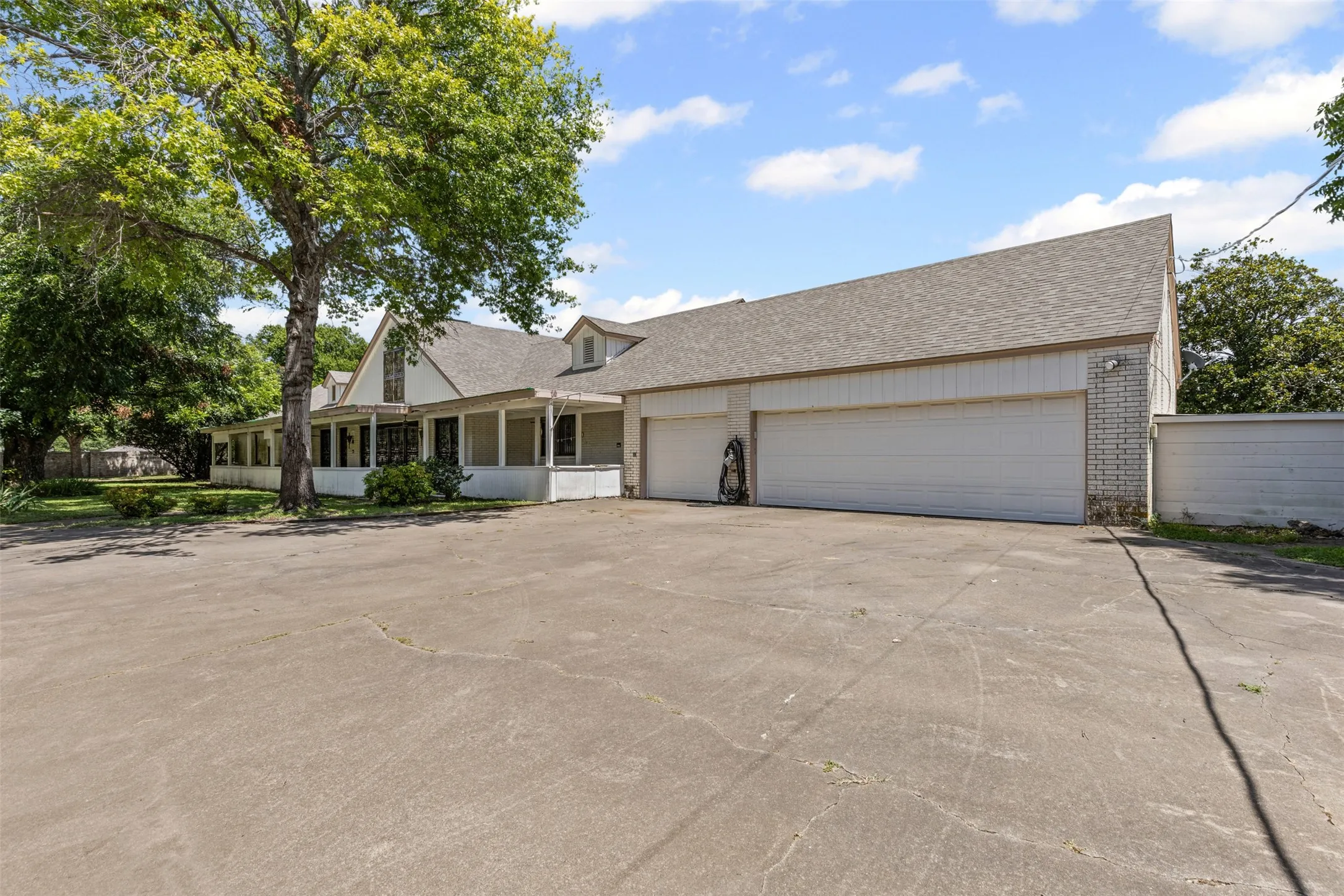 View of front of house with brick siding, a shingled roof, driveway, and a garage