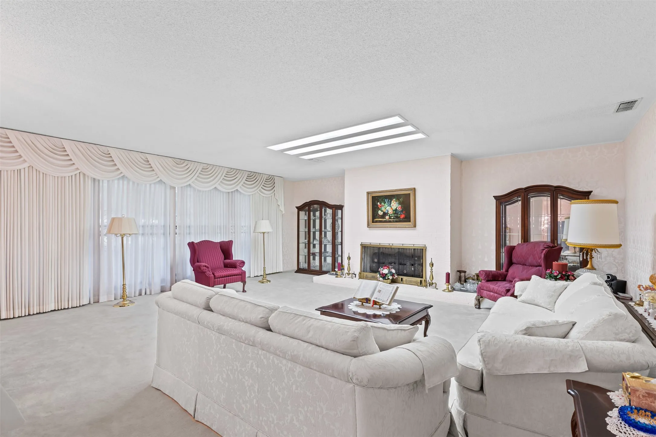 Carpeted living area with a glass covered fireplace and a textured ceiling