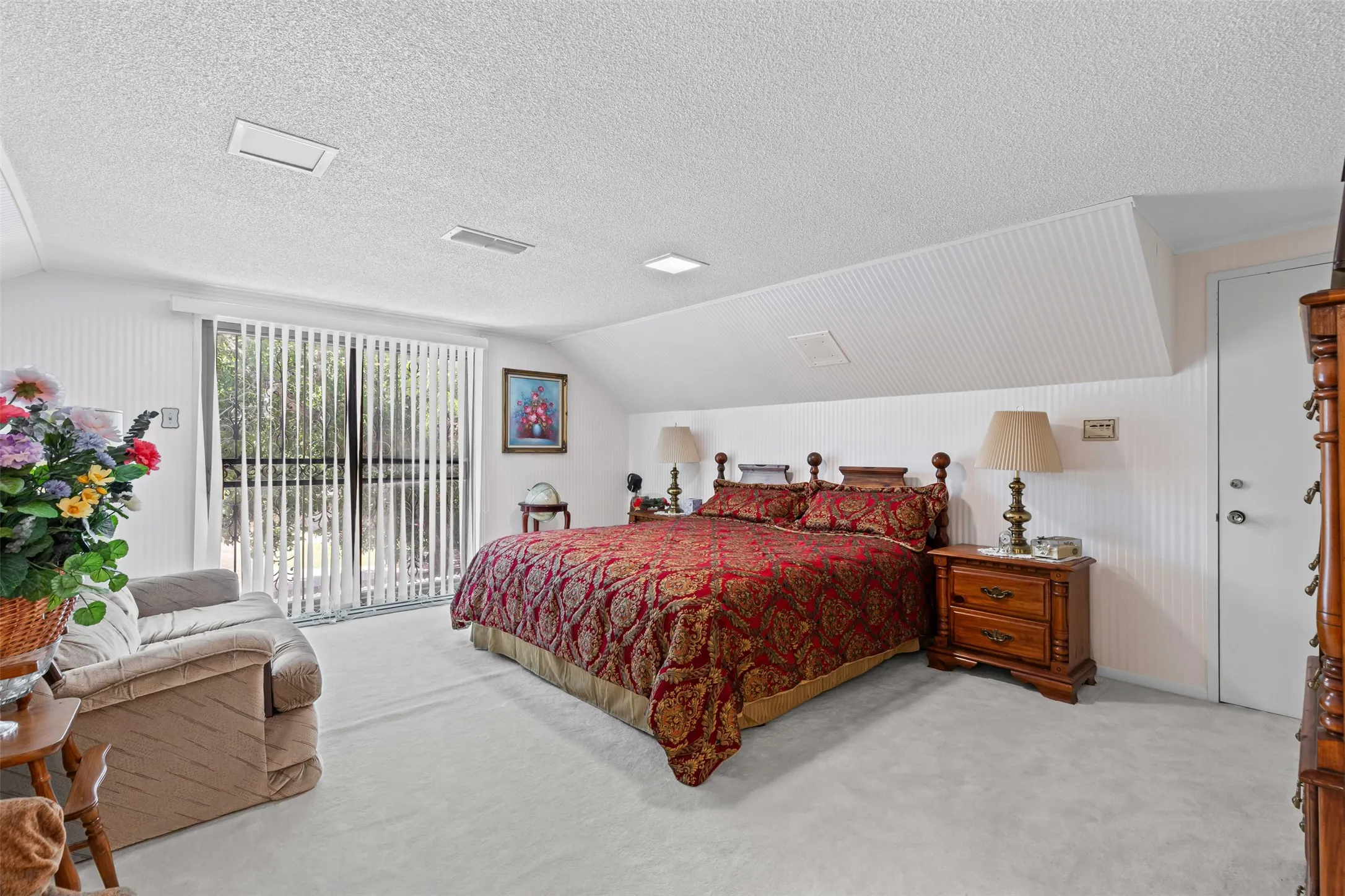 Bedroom featuring access to outside, lofted ceiling, carpet flooring, and a textured ceiling