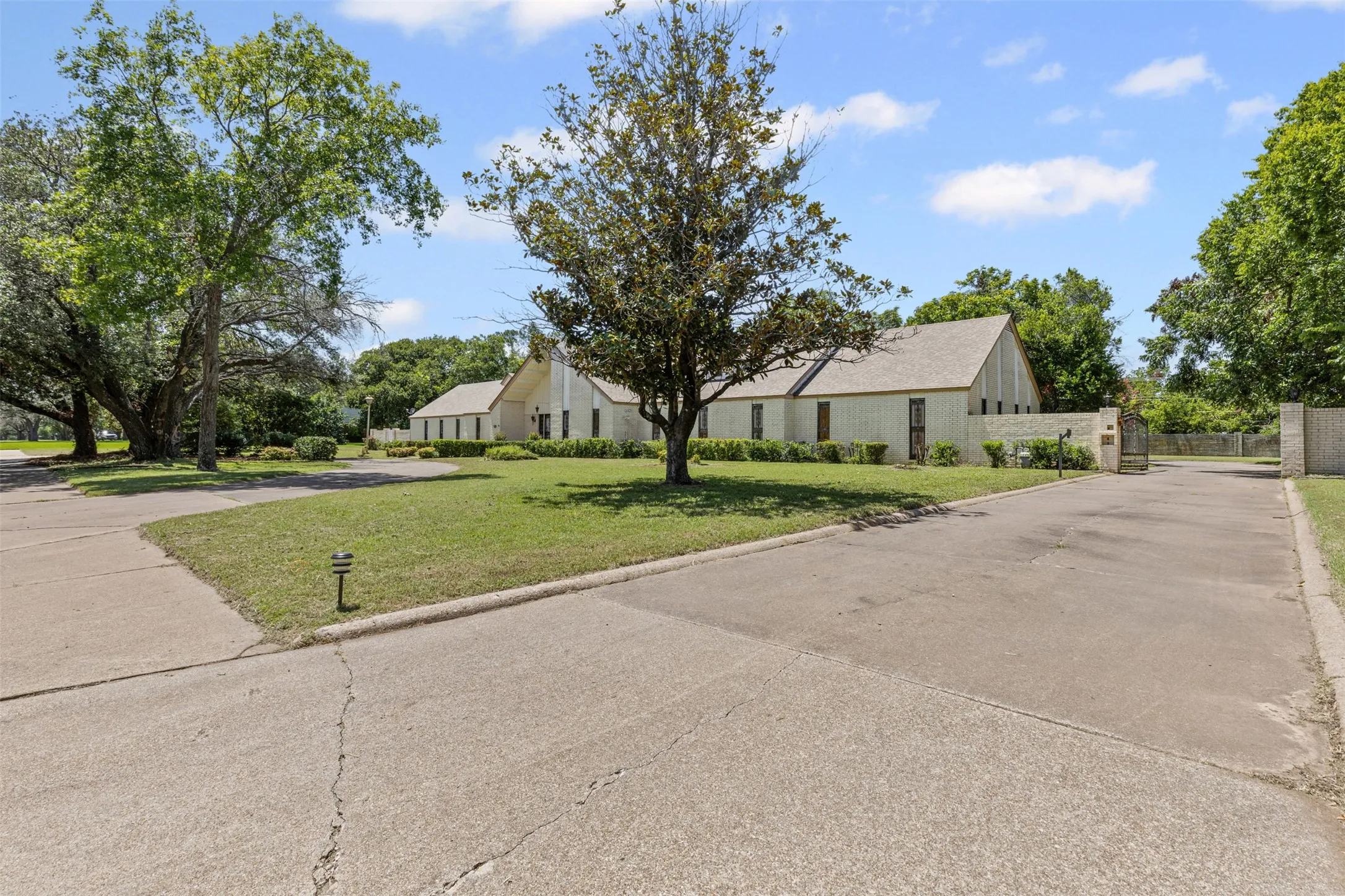View of front facade with concrete driveway, a gate, and brick siding