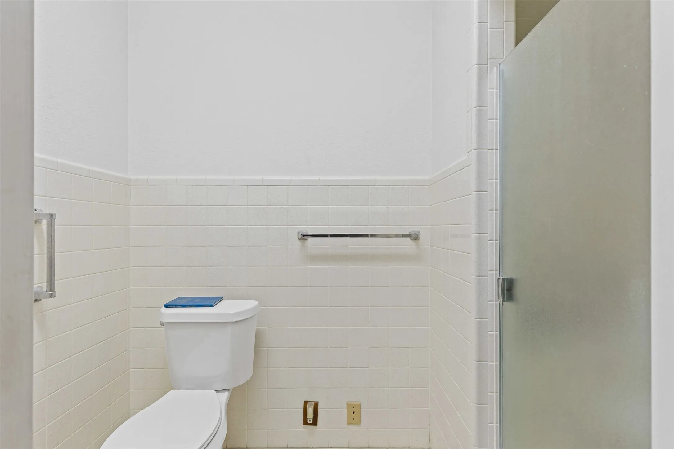 Full bathroom featuring tile walls, a stall shower, and wainscoting