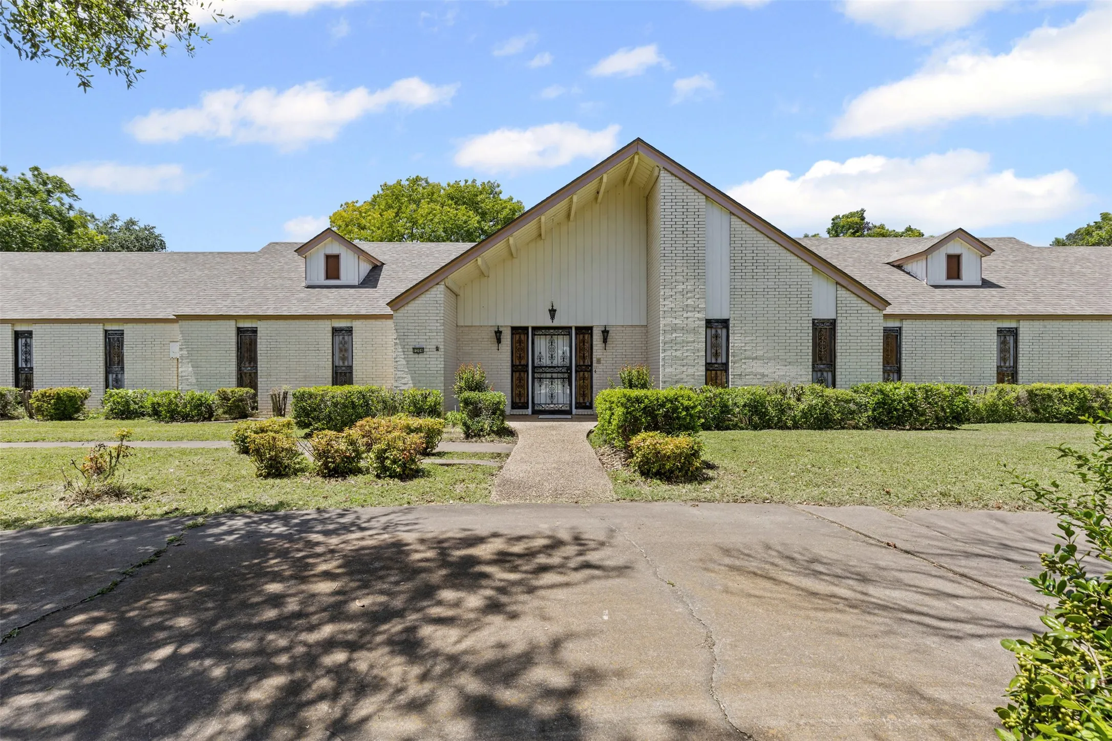 View of front of home featuring brick siding, a front yard, and roof with shingles