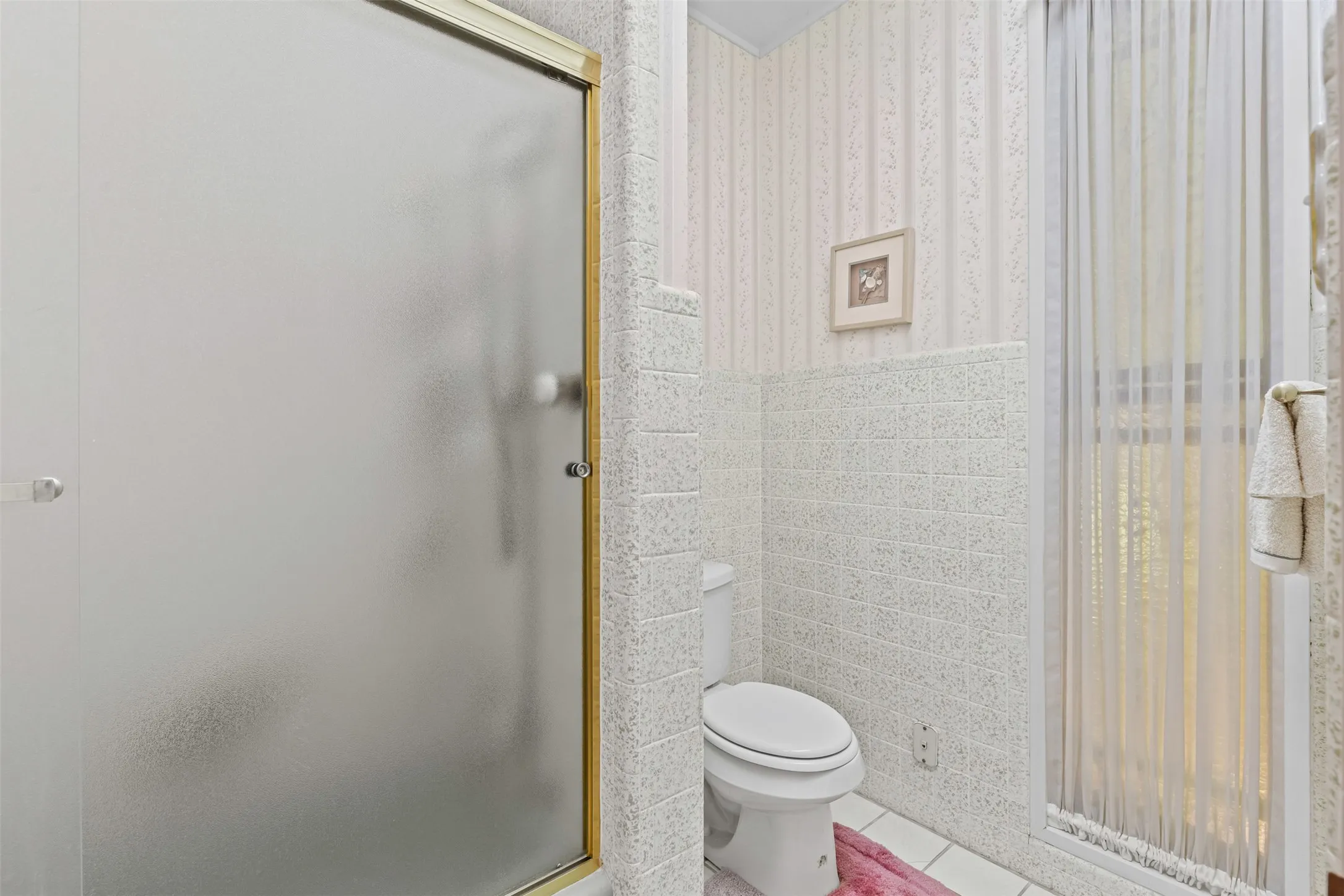 Full bathroom featuring a shower stall, tile patterned floors, tile walls, and wallpapered walls