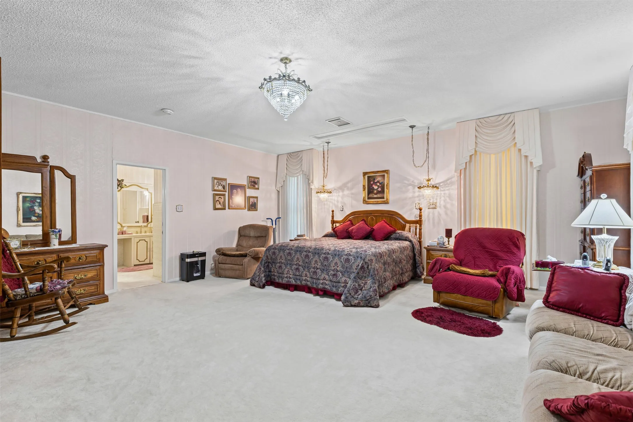 Bedroom with a chandelier, carpet floors, a textured ceiling, and ensuite bath