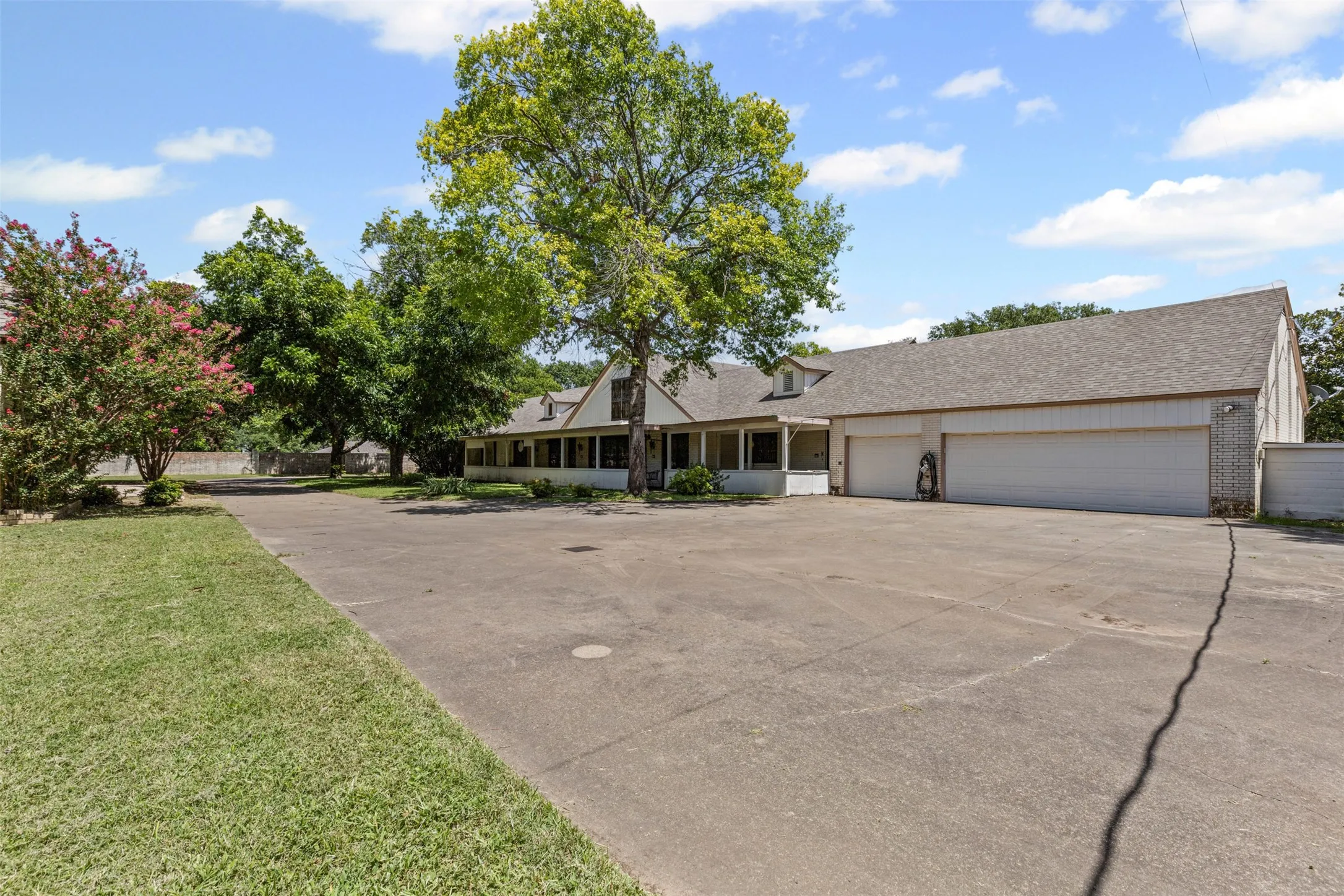 View of front facade with driveway, a garage, brick siding, a front yard, and roof with shingles