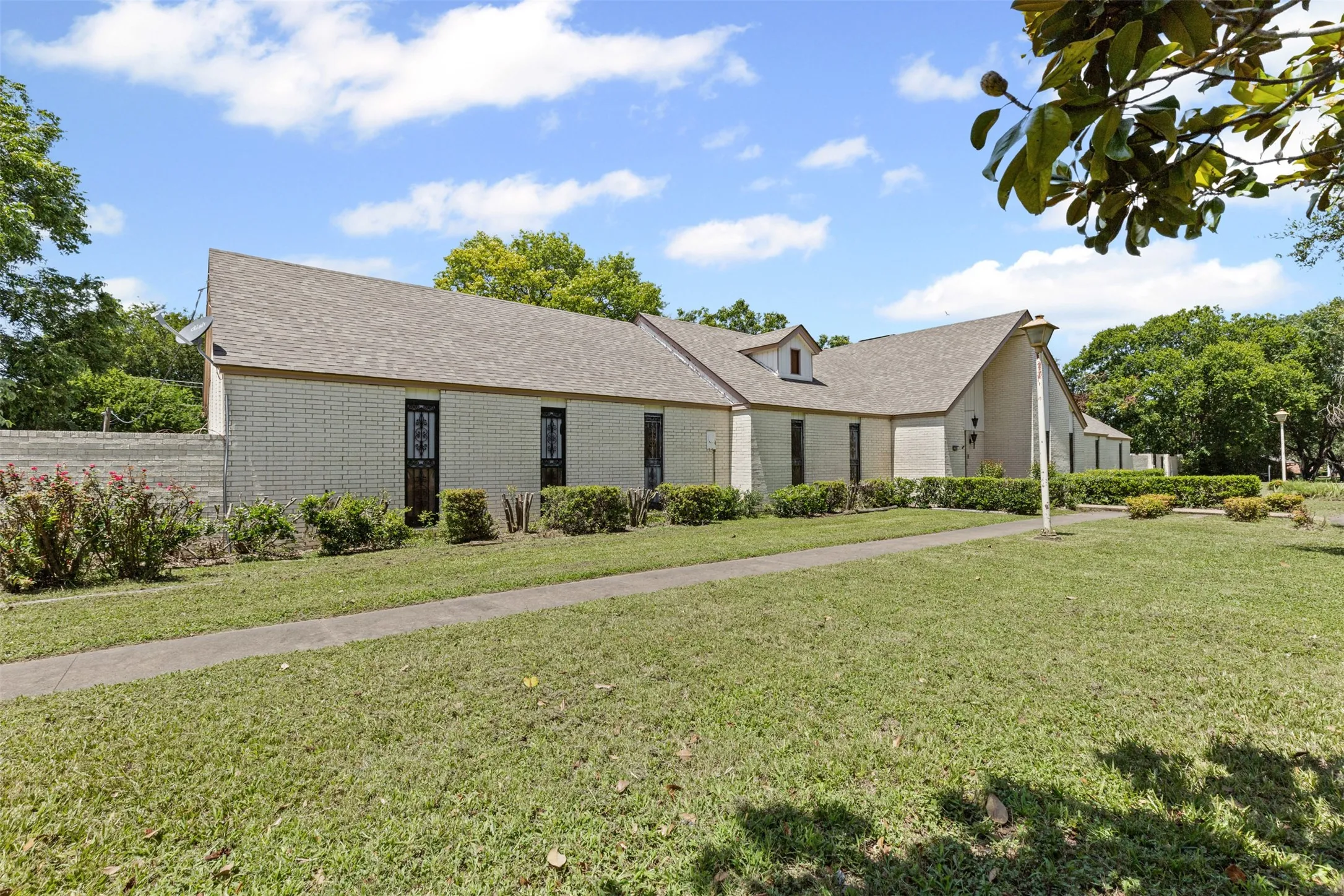 View of front of house with brick siding, a shingled roof, and a front yard
